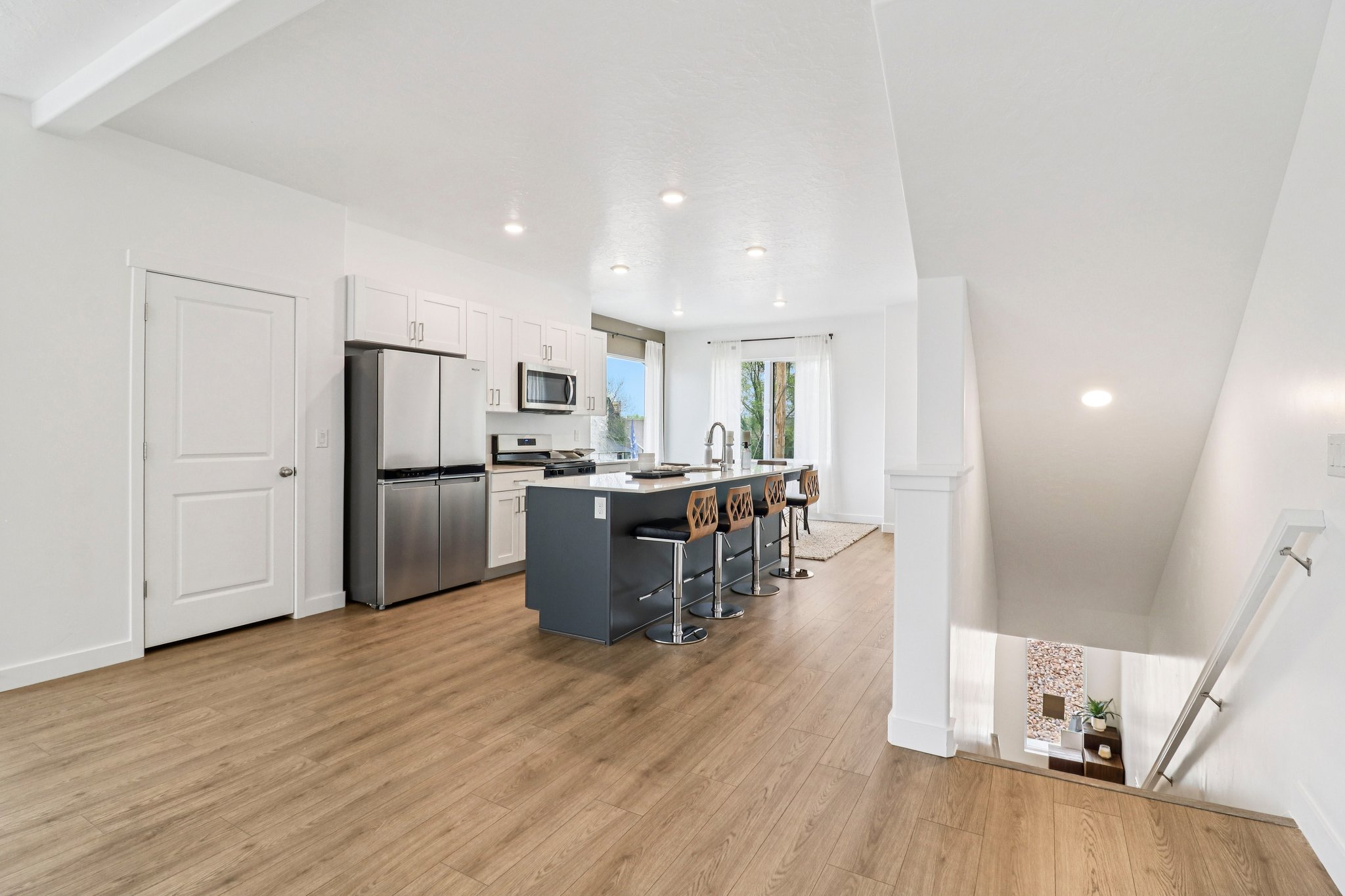 Open-concept kitchen featuring white cabinetry, stainless steel appliances, and a central island with seating