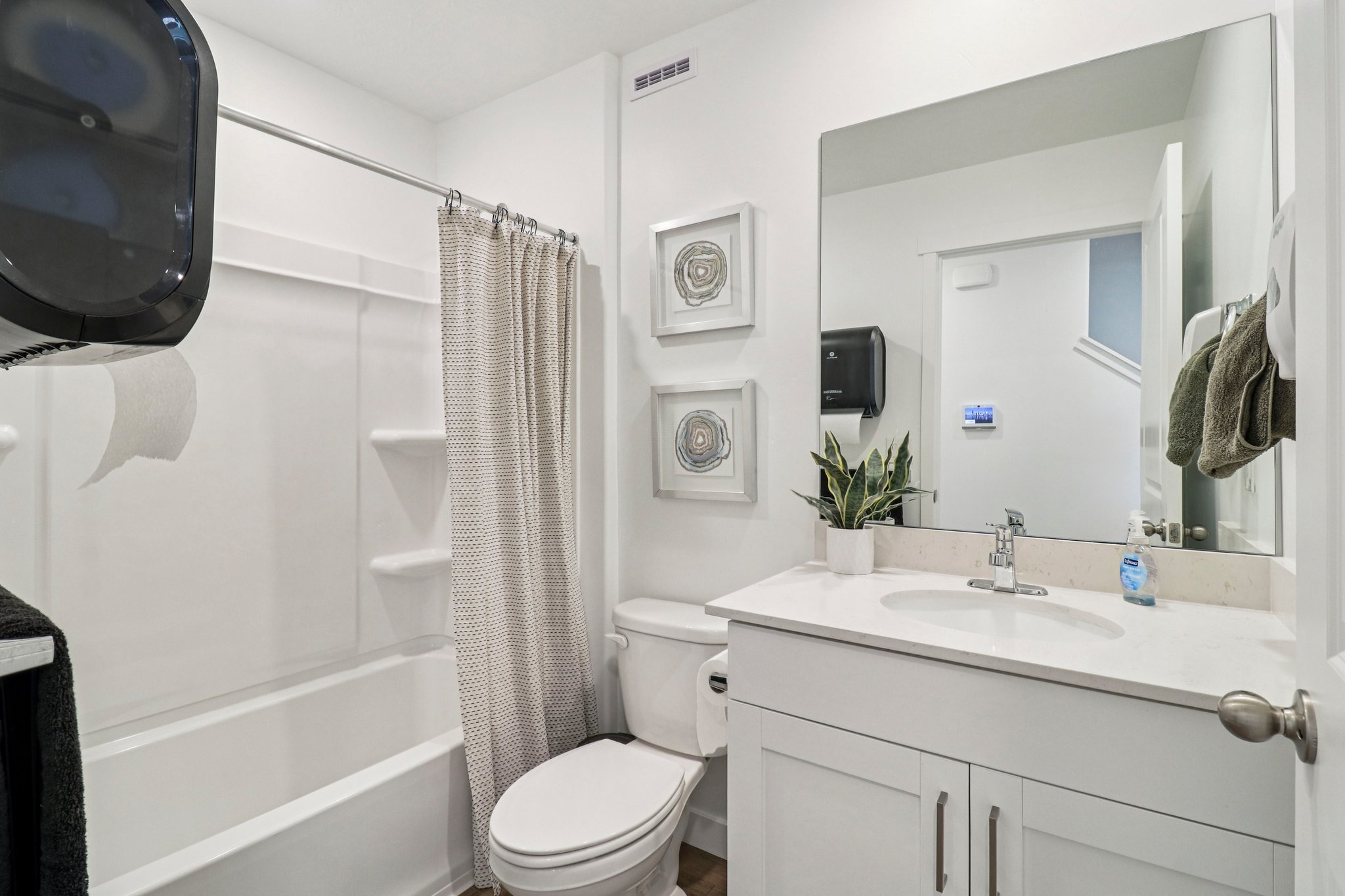 White bathroom featuring a single vanity with a solid surface countertop, an undermount sink, and a chrome faucet