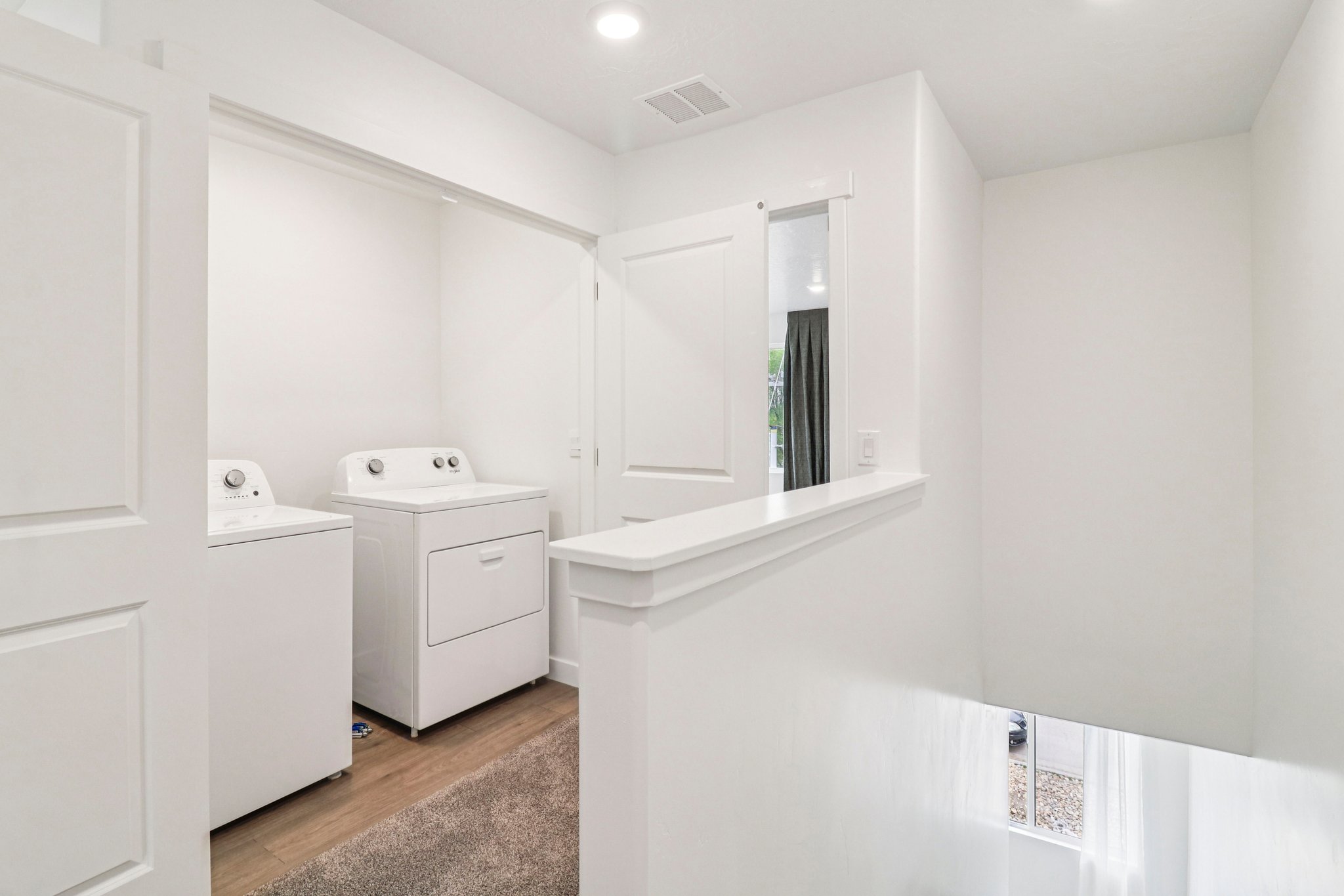Dedicated laundry alcove featuring recessed lighting, a white washer and dryer, and wood-finish flooring