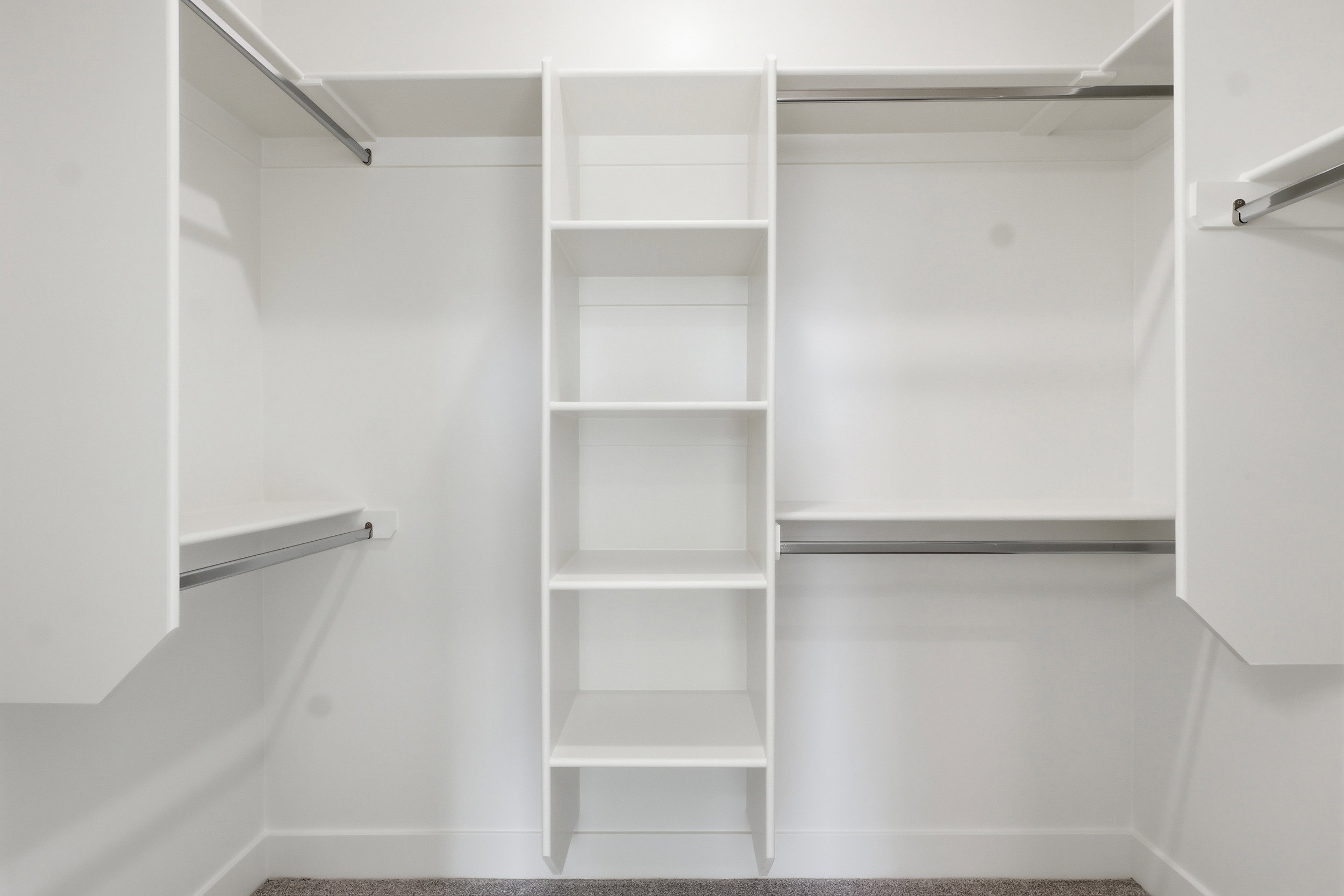White custom closet system featuring integrated shelving and multiple hanging rods