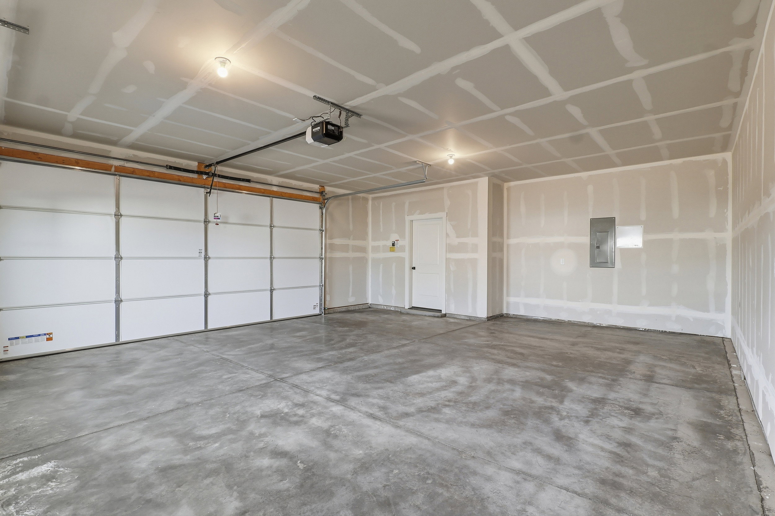 Spacious garage featuring a concrete floor, overhead lighting, and an automatic garage door opener