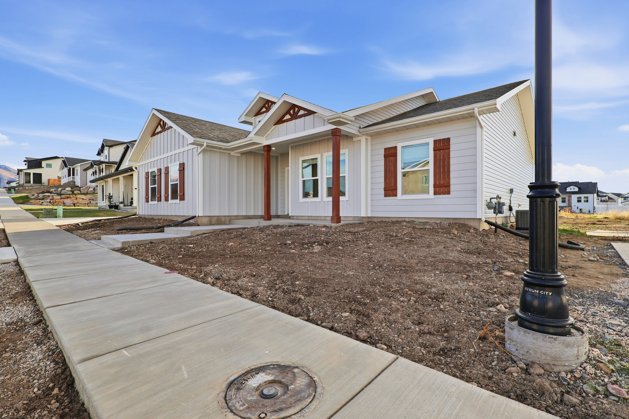 Contemporary ranch-style home featuring light gray siding and dark brown shutters