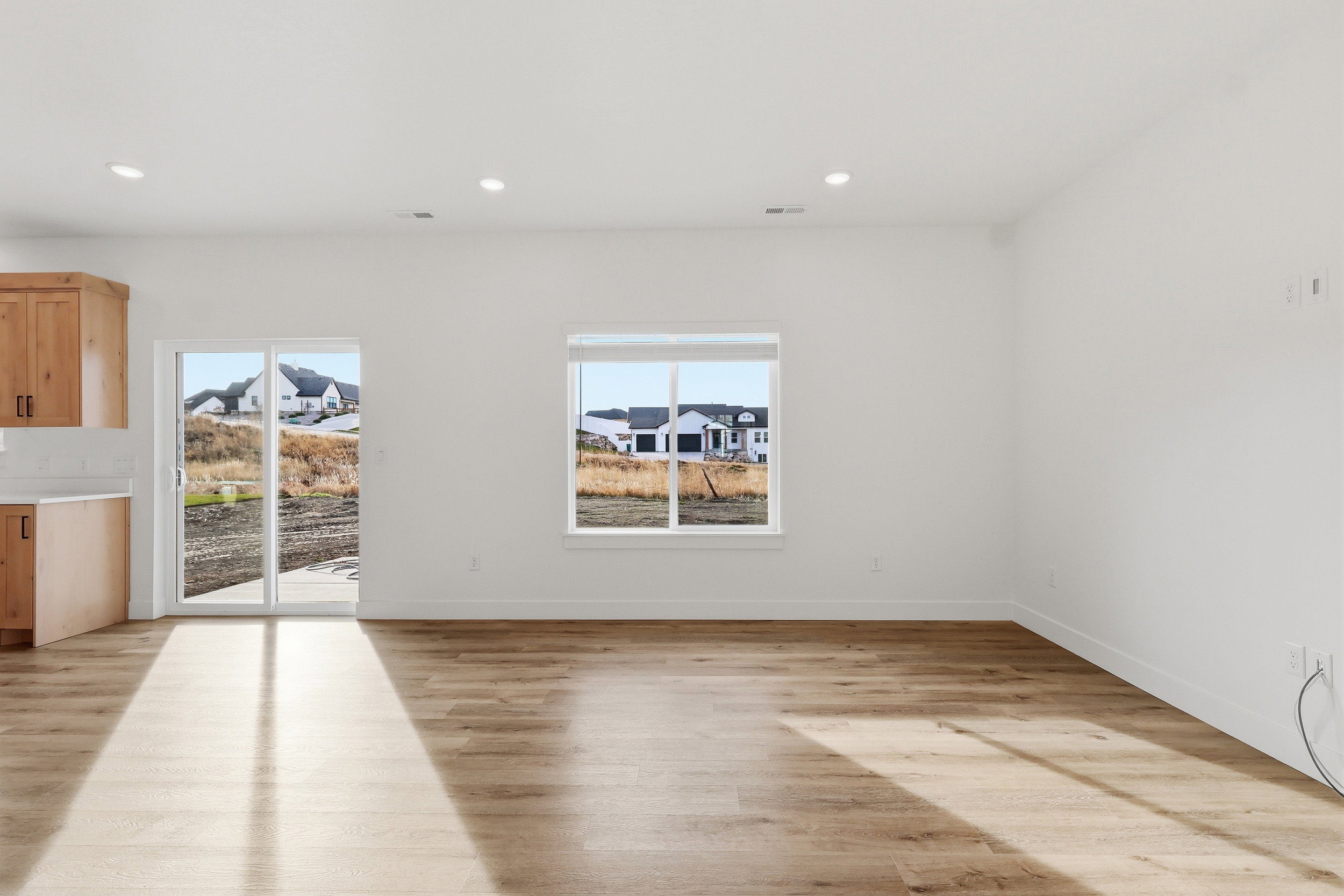 Spacious room featuring wood-finish flooring, white walls, and recessed lighting
