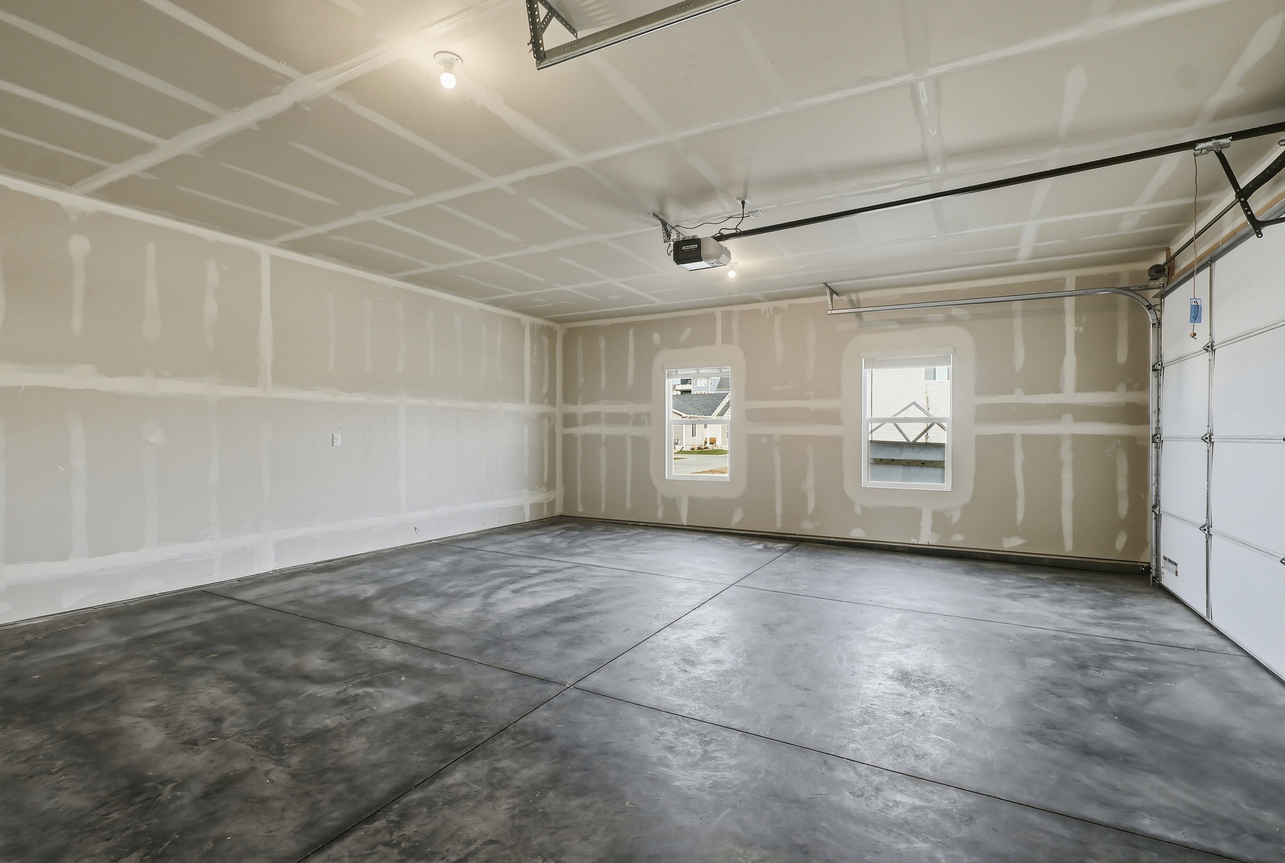 Spacious two-car garage featuring a concrete floor, two windows, and an automatic garage door opener