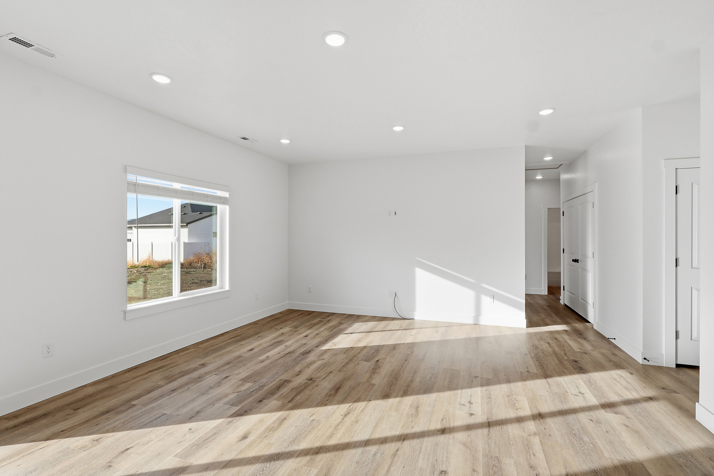 Open-concept living space featuring wood-finish flooring, recessed ceiling lighting, and a large window