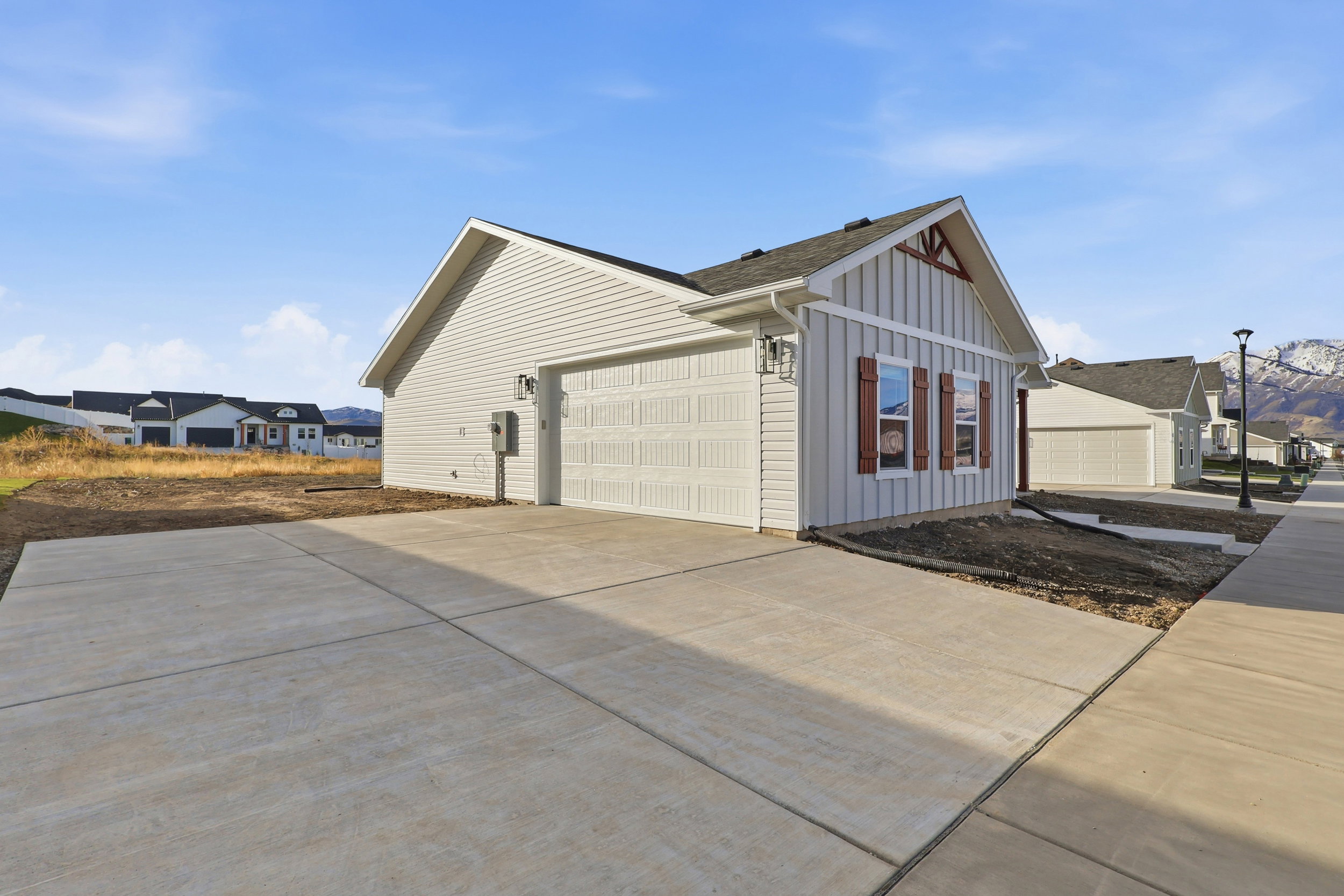 Contemporary single-story residence featuring light-colored horizontal siding and a prominent gable with vertical board and batten siding