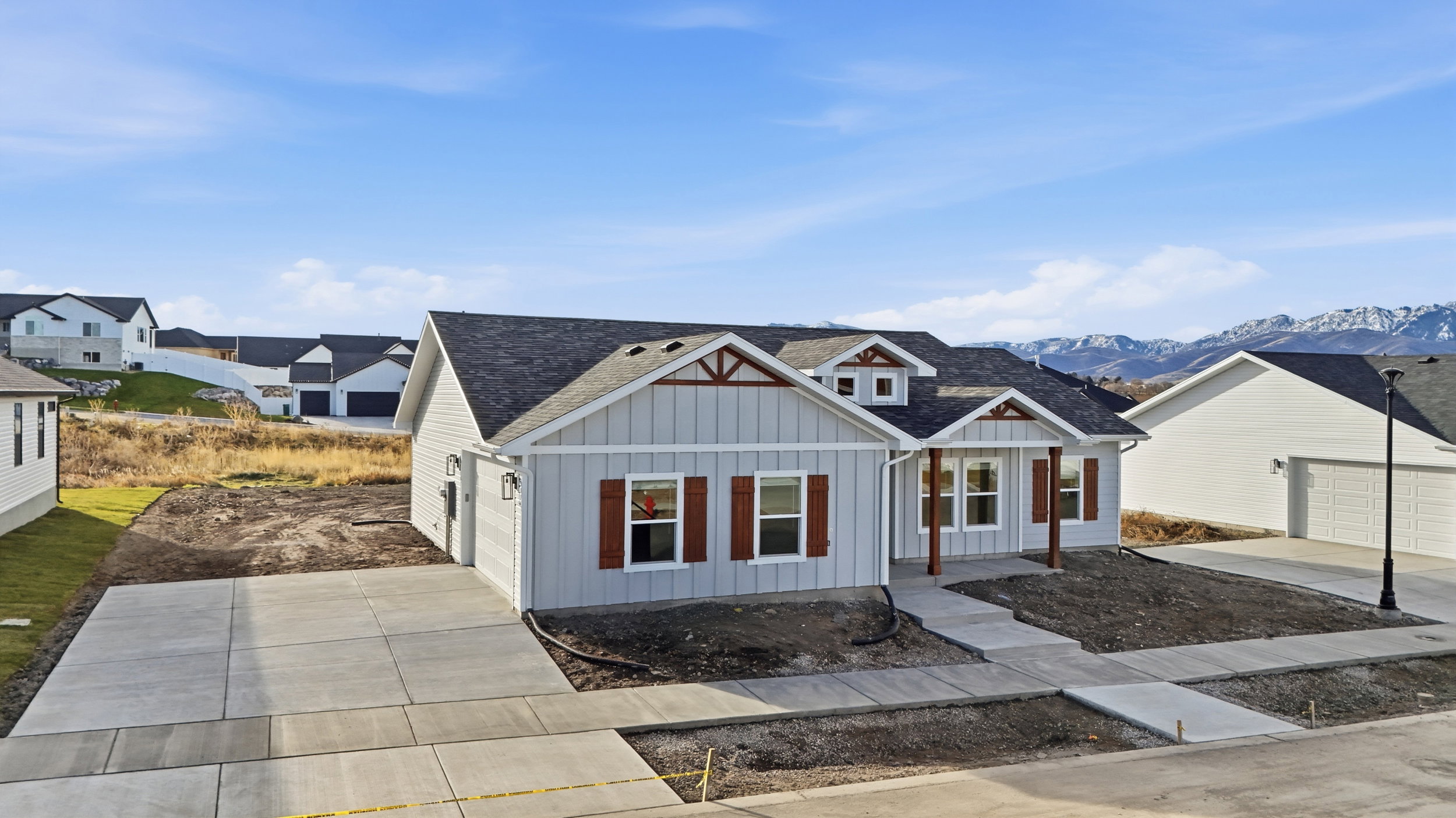 Light gray siding exterior with dark brown trim accents, featuring a covered front porch with wood-look columns