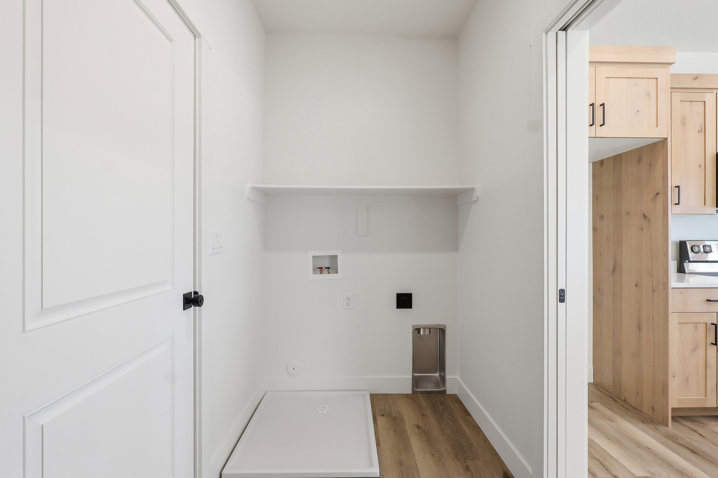 Dedicated laundry area featuring a utility shelf and wood-finish flooring