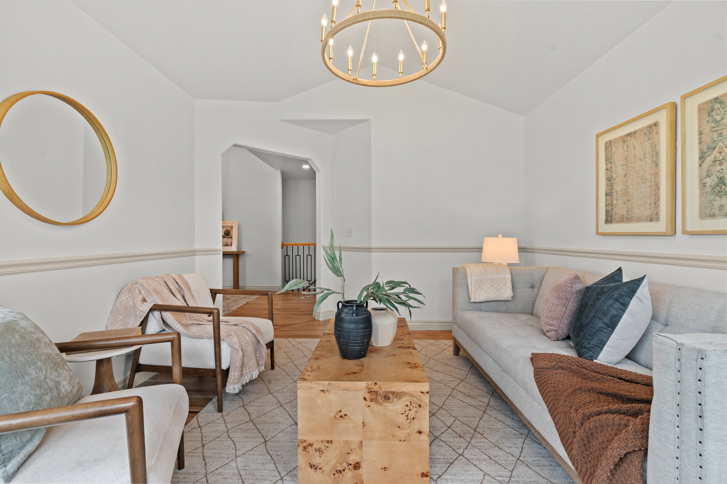Vaulted ceiling with an ornate chandelier, hardwood flooring, and a decorative archway