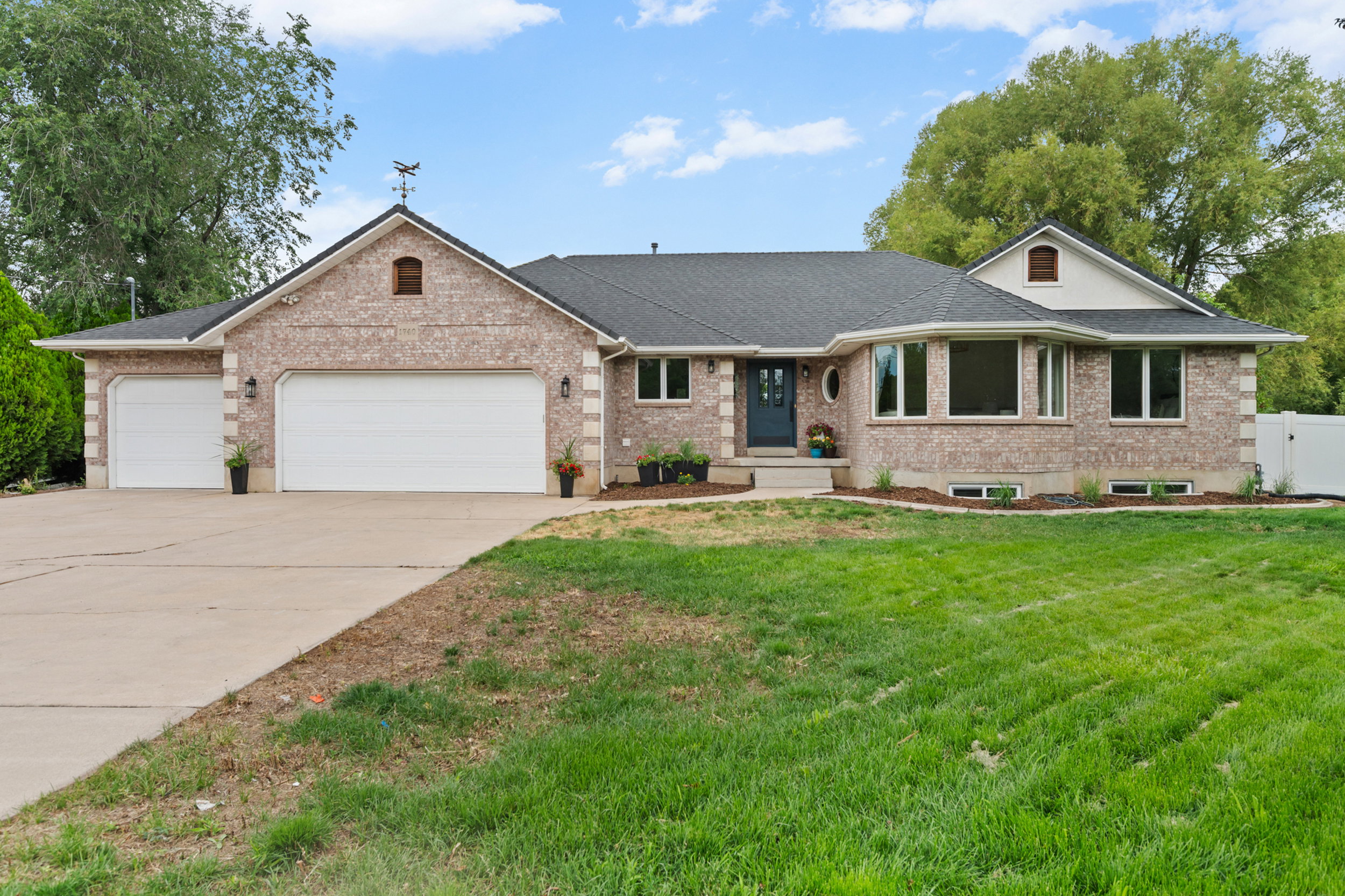Brick exterior featuring a multi-bay garage, dark roof, and a prominent bay window