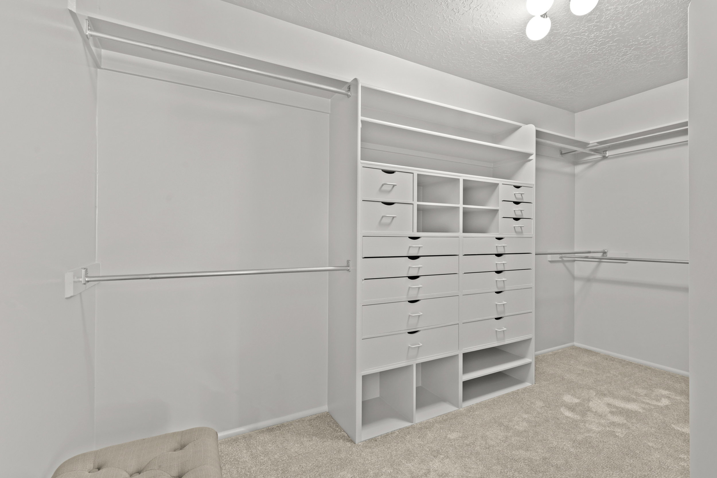 Custom closet system featuring multiple drawers, open shelving, and hanging rods