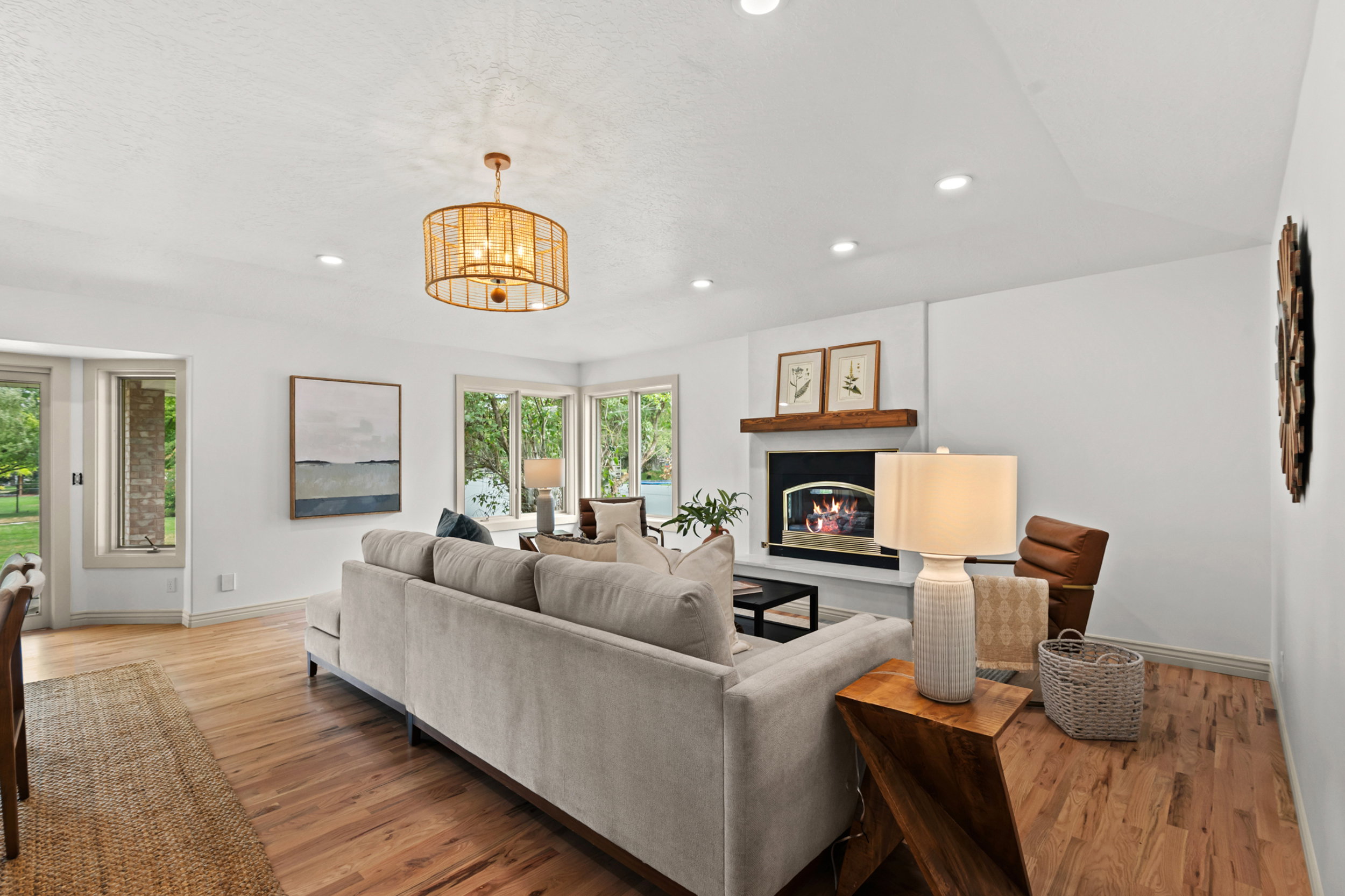 Living area featuring hardwood flooring, a fireplace with a wood mantel, a bay window, recessed lighting, and a decorative chandelier