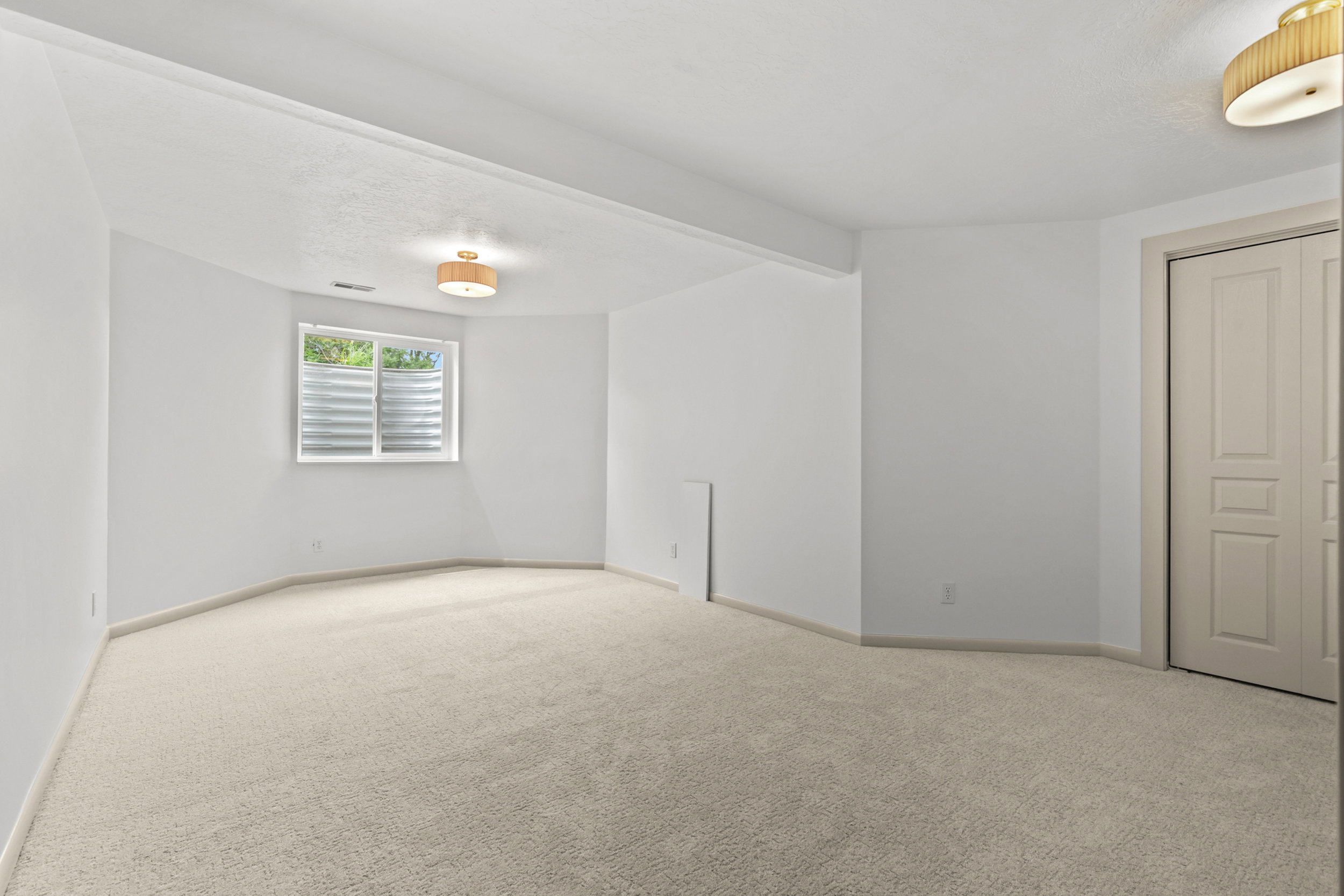 Carpeted room featuring a single window, white walls, and two flush mount light fixtures