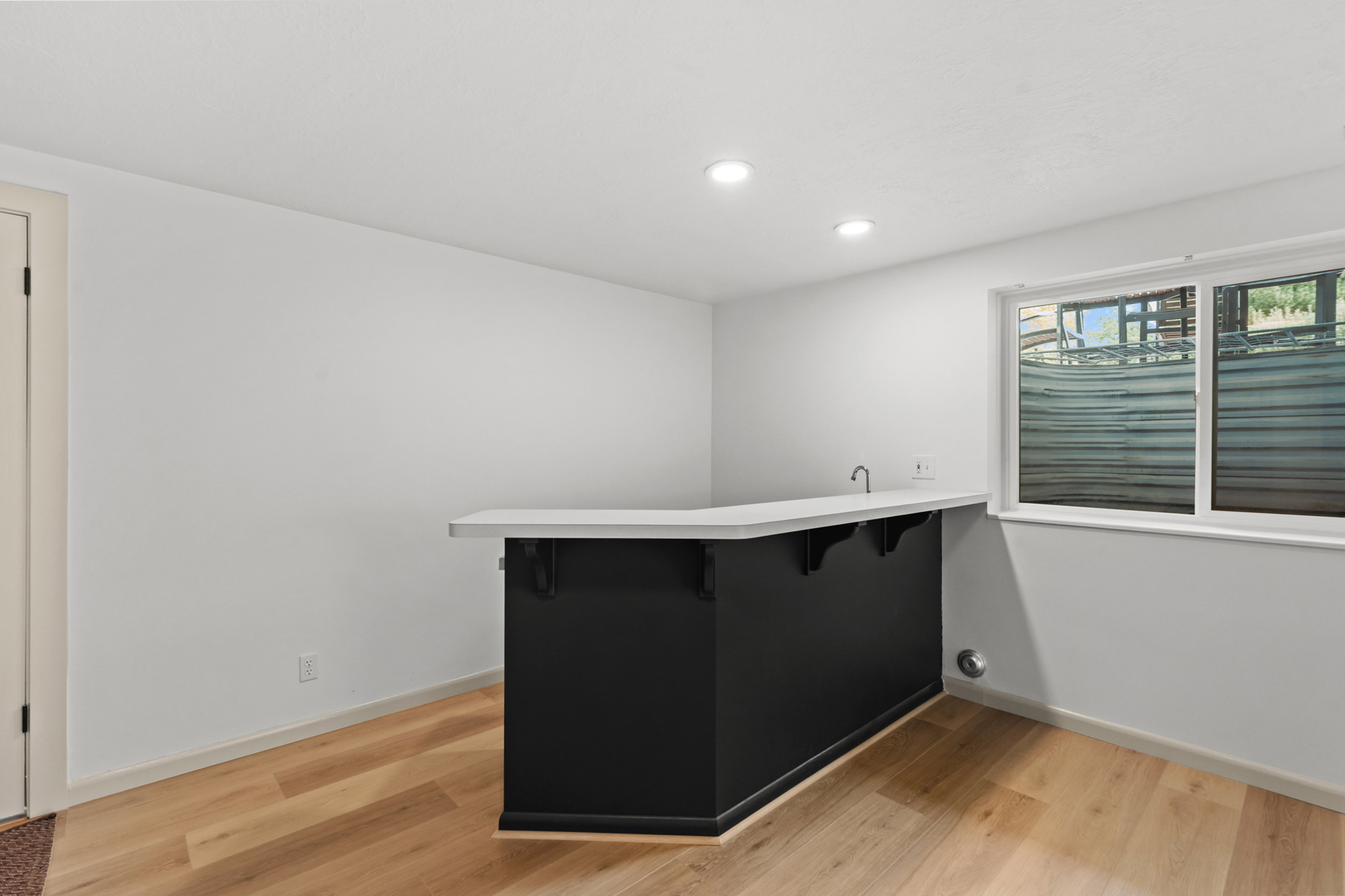 Entertainment space featuring a built-in wet bar with a light-toned countertop and dark cabinetry