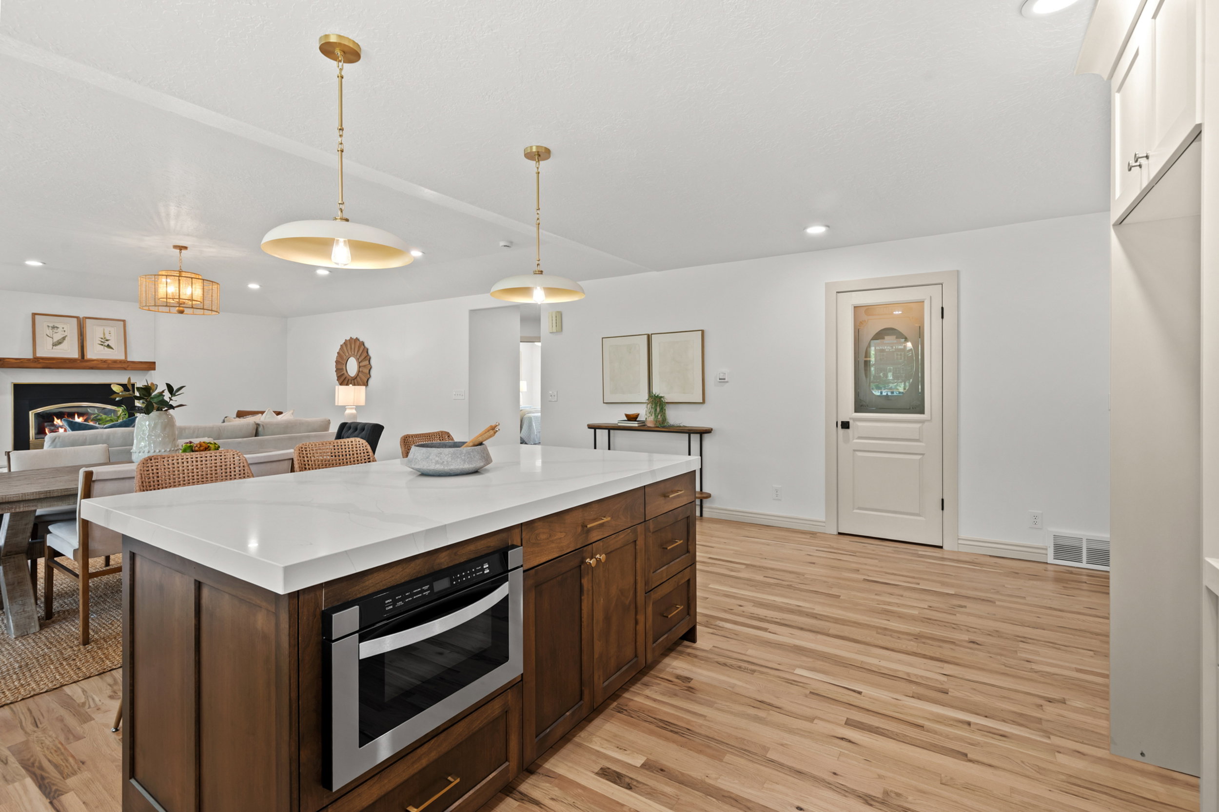 Kitchen island with a white countertop and integrated microwave drawer, complemented by wood-finish flooring
