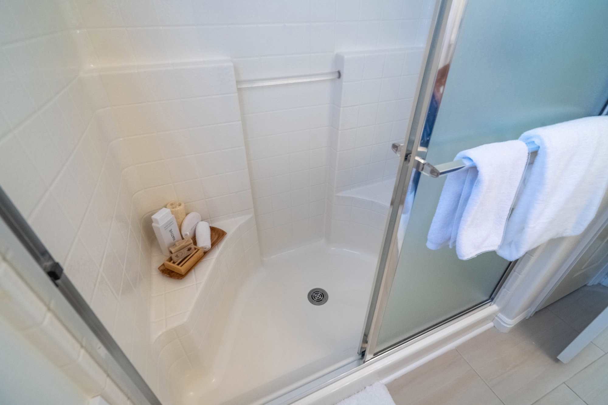 Shower enclosure with a built-in corner bench and integrated shelving