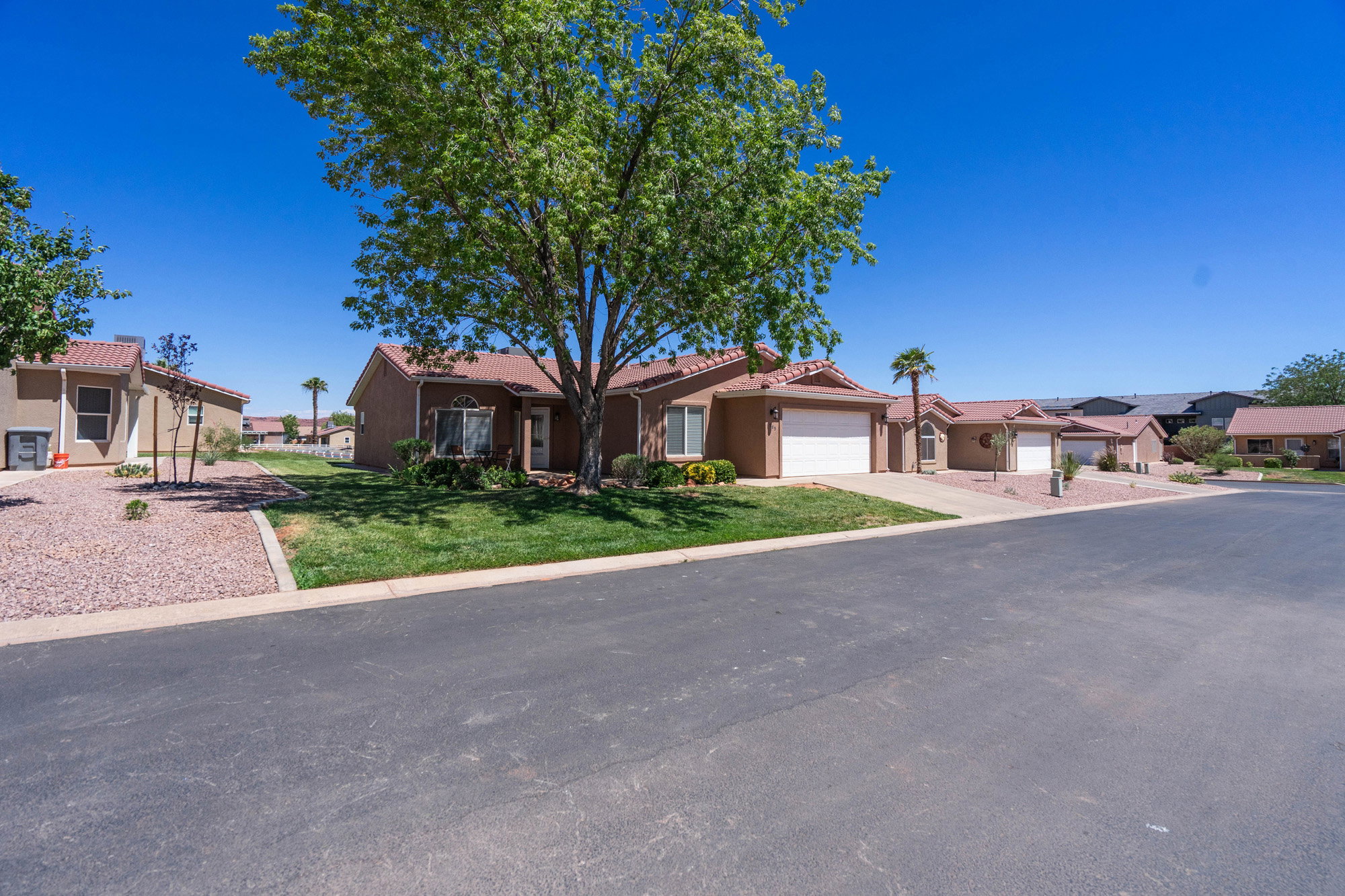Southwestern-style residence featuring a stucco exterior, terra cotta roof tiles, and an attached two-car garage