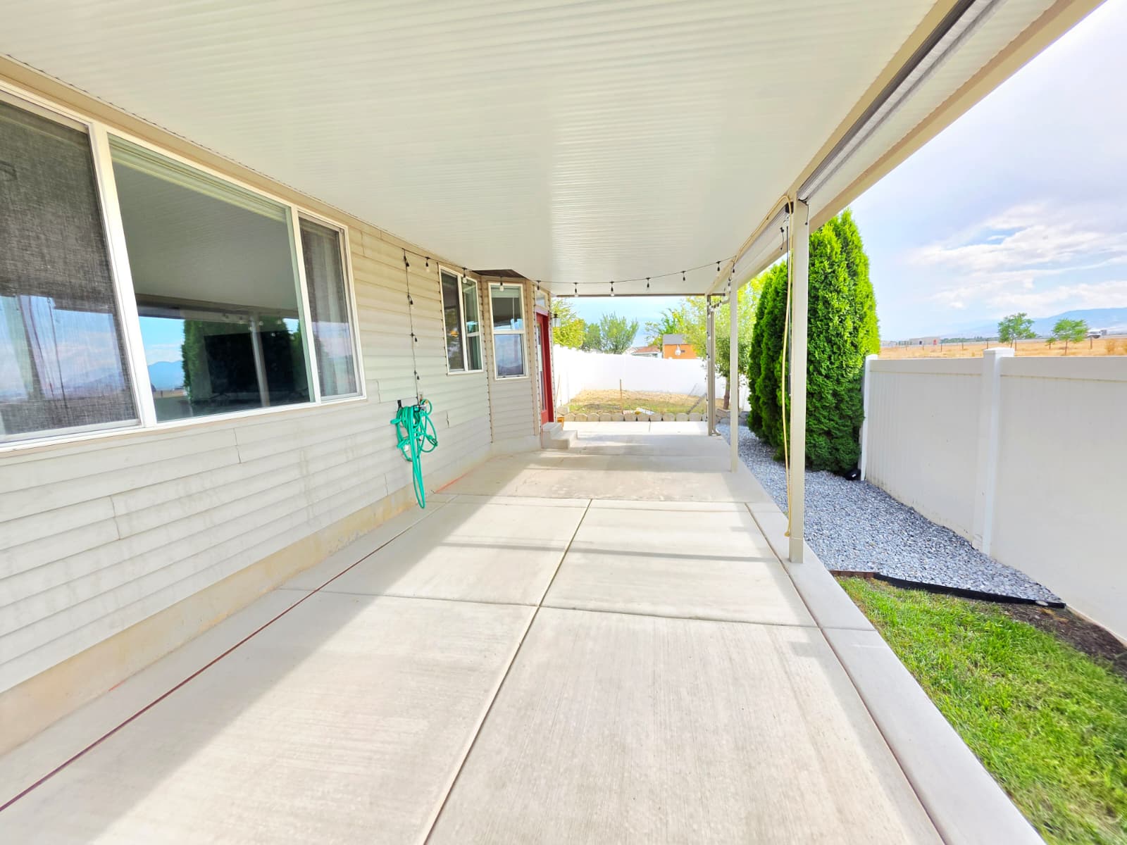 Expansive covered patio featuring a corrugated metal roof, string lighting, and direct access to the interior