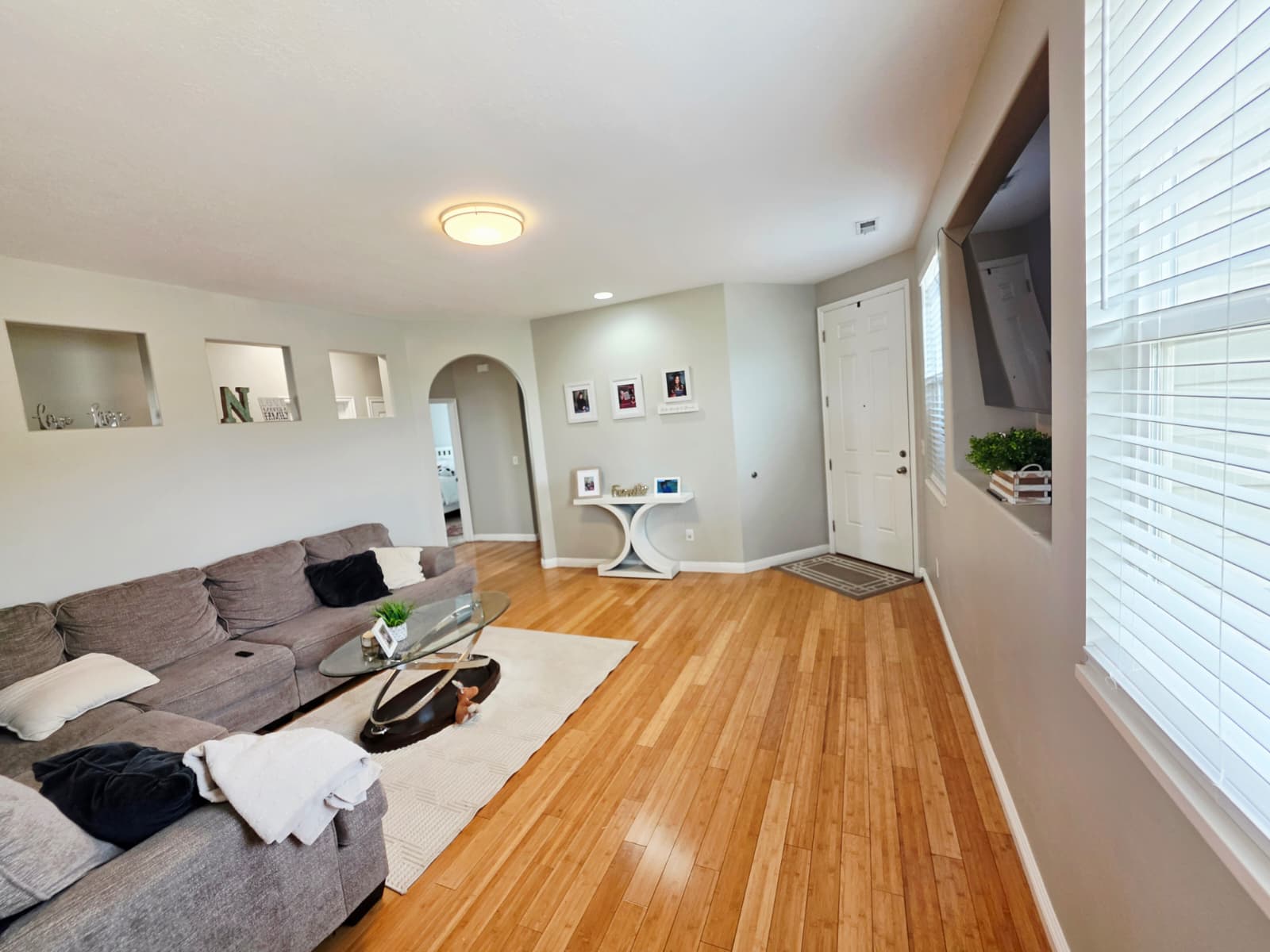 Expansive living area featuring wood-finish flooring, recessed wall niches, and an arched doorway