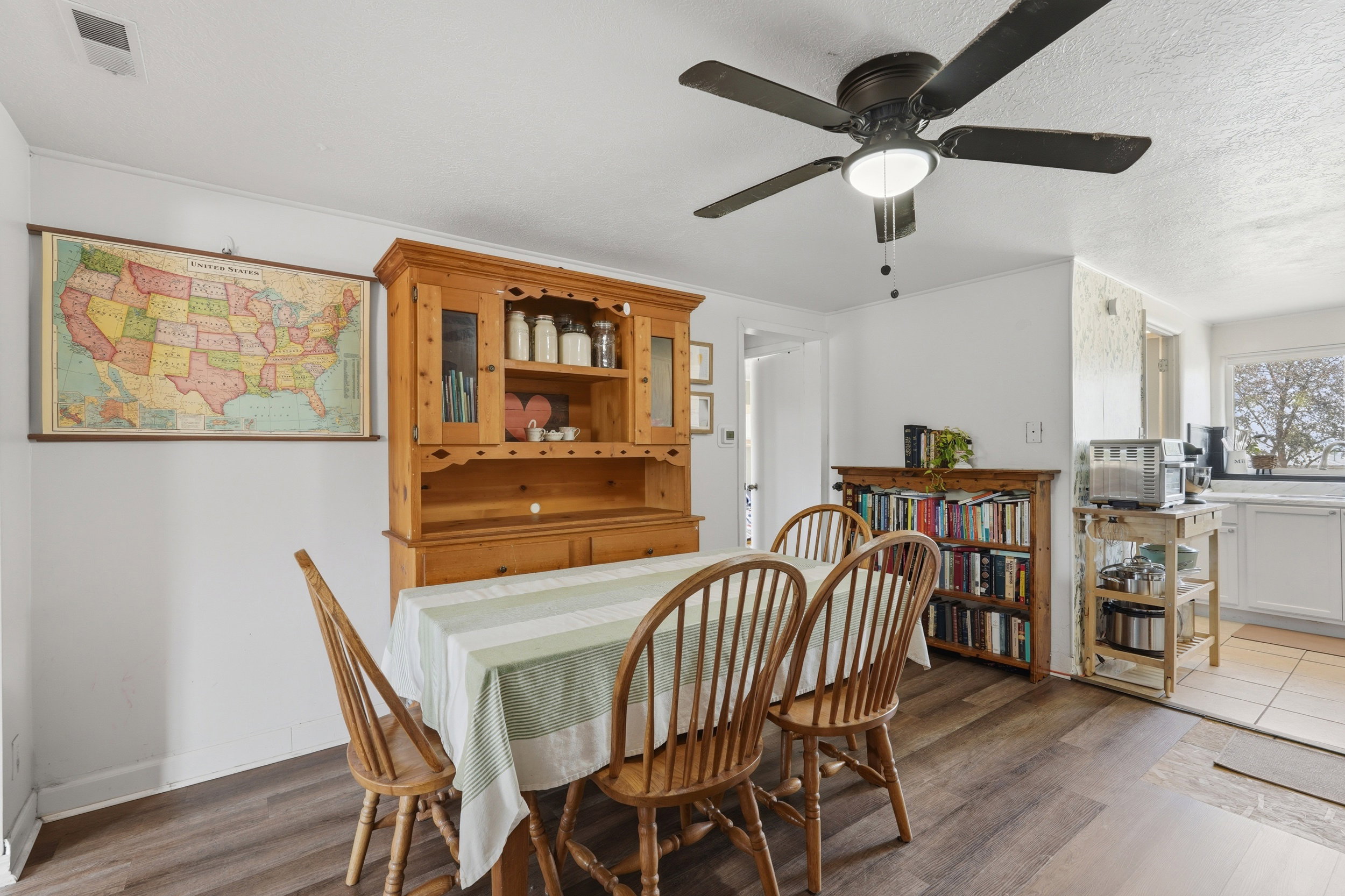 Dining area with wood-finish flooring, a ceiling fan with integrated lighting, and a built-in hutch