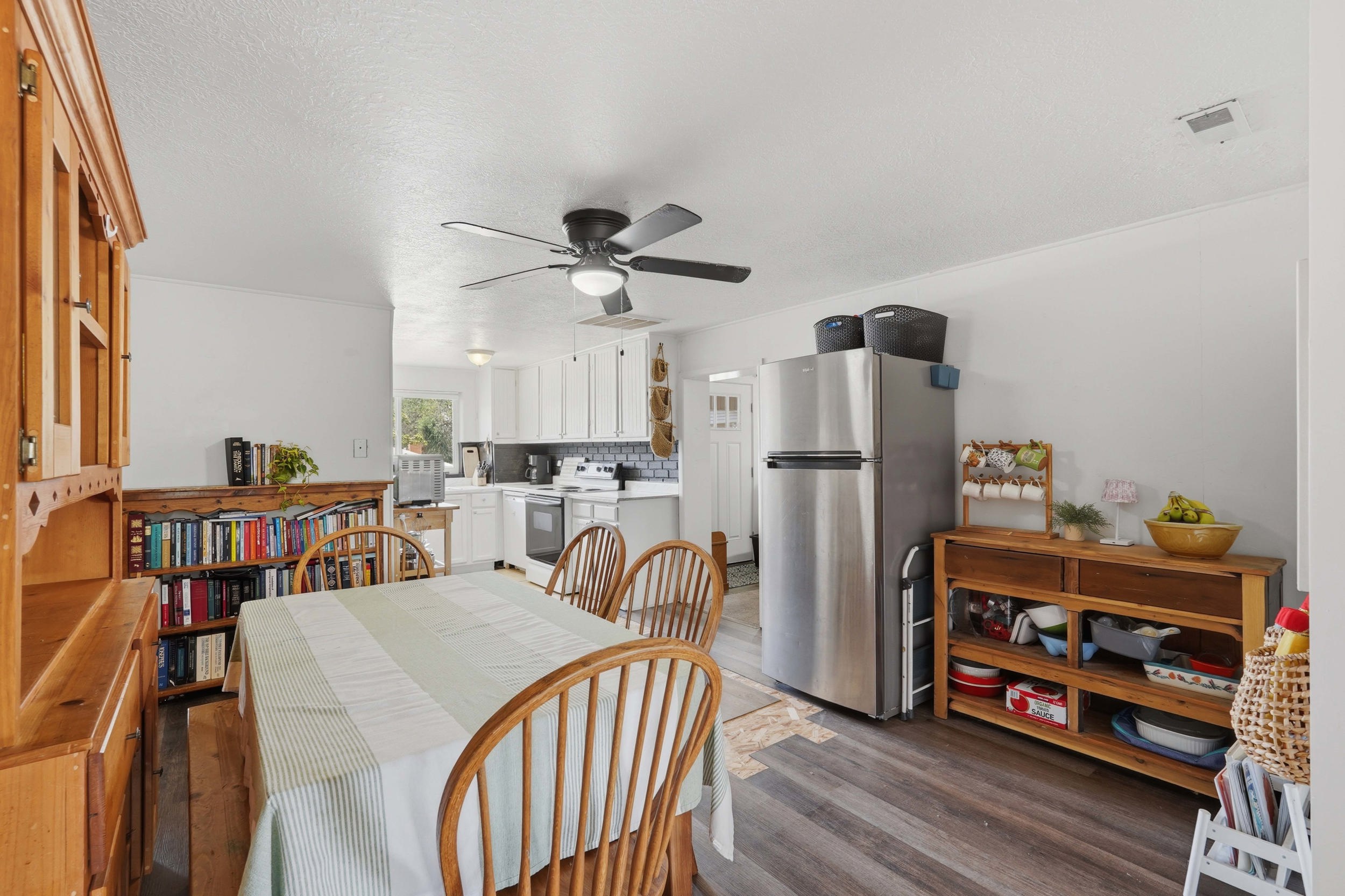 Kitchen and dining area featuring wood-finish flooring, white cabinetry, and stainless steel appliances