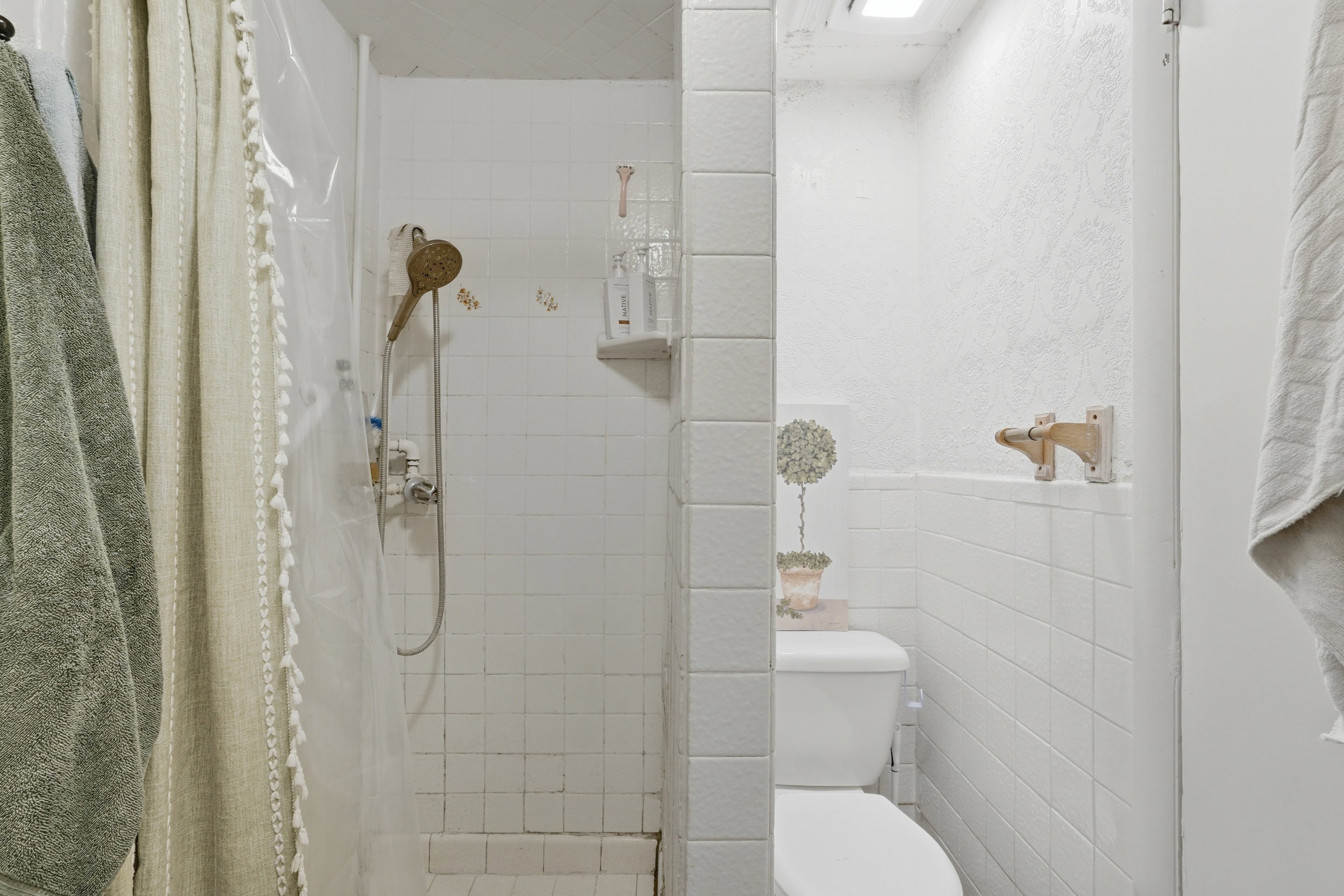 White tile shower stall with a handheld showerhead