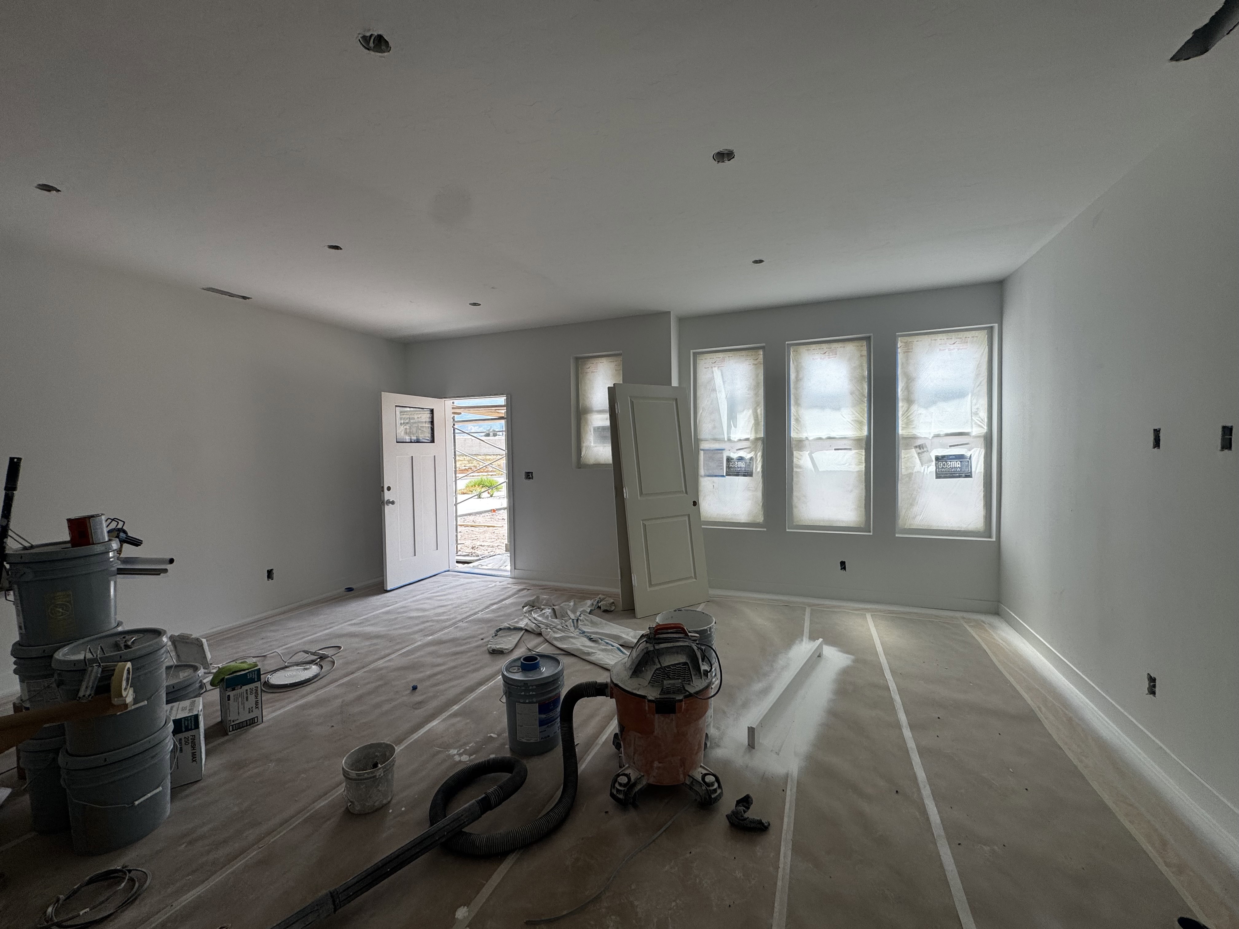Spacious room featuring multiple windows, a paneled entry door with a decorative glass insert, and recessed ceiling lighting