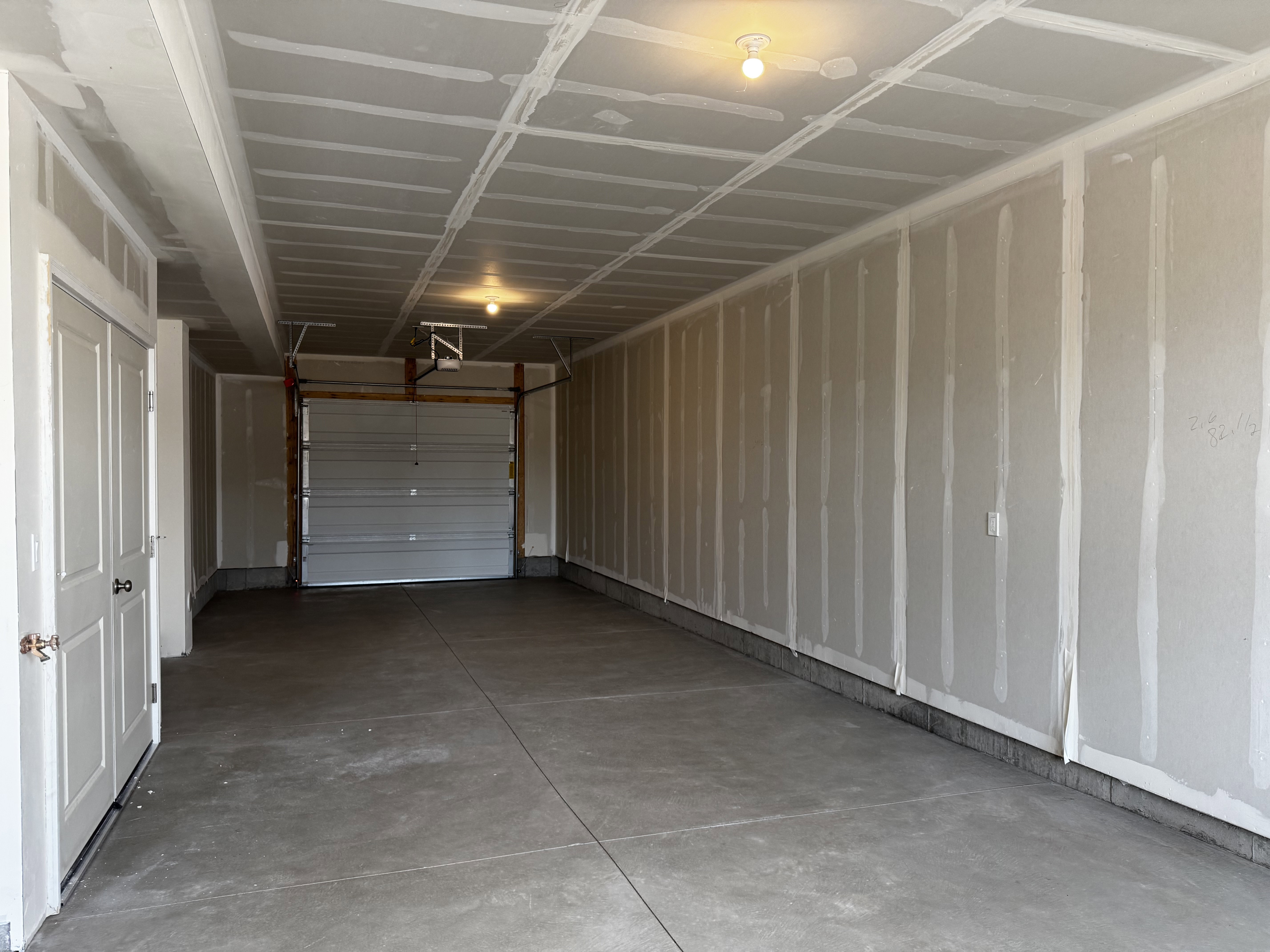 Attached garage featuring a concrete floor, overhead lighting, and an automatic garage door