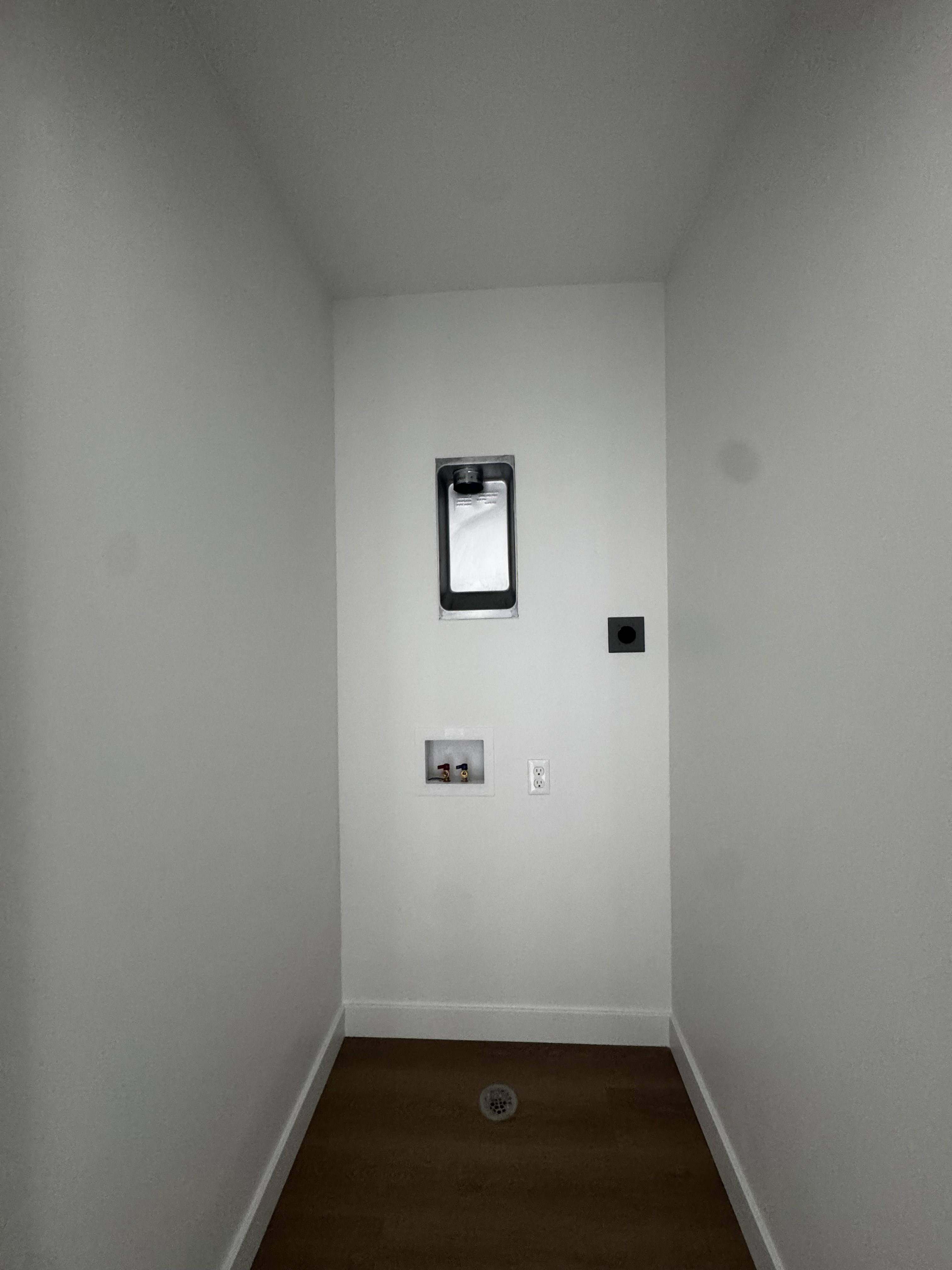 Dedicated utility area featuring wood-finish flooring, white walls, and bright white baseboards
