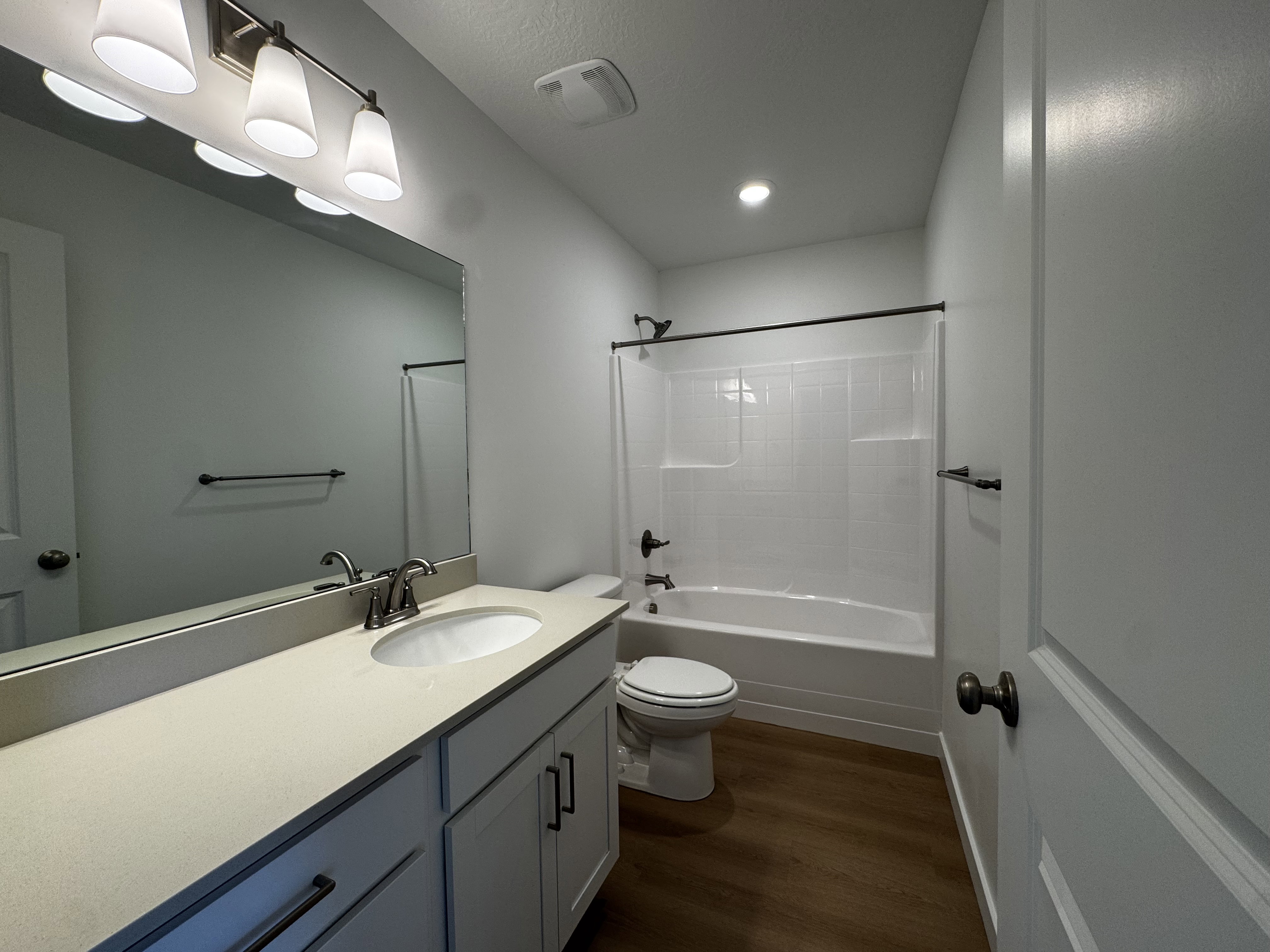 Bathroom featuring a single vanity with light-toned countertop, white cabinetry, undermount sink, and brushed nickel faucet