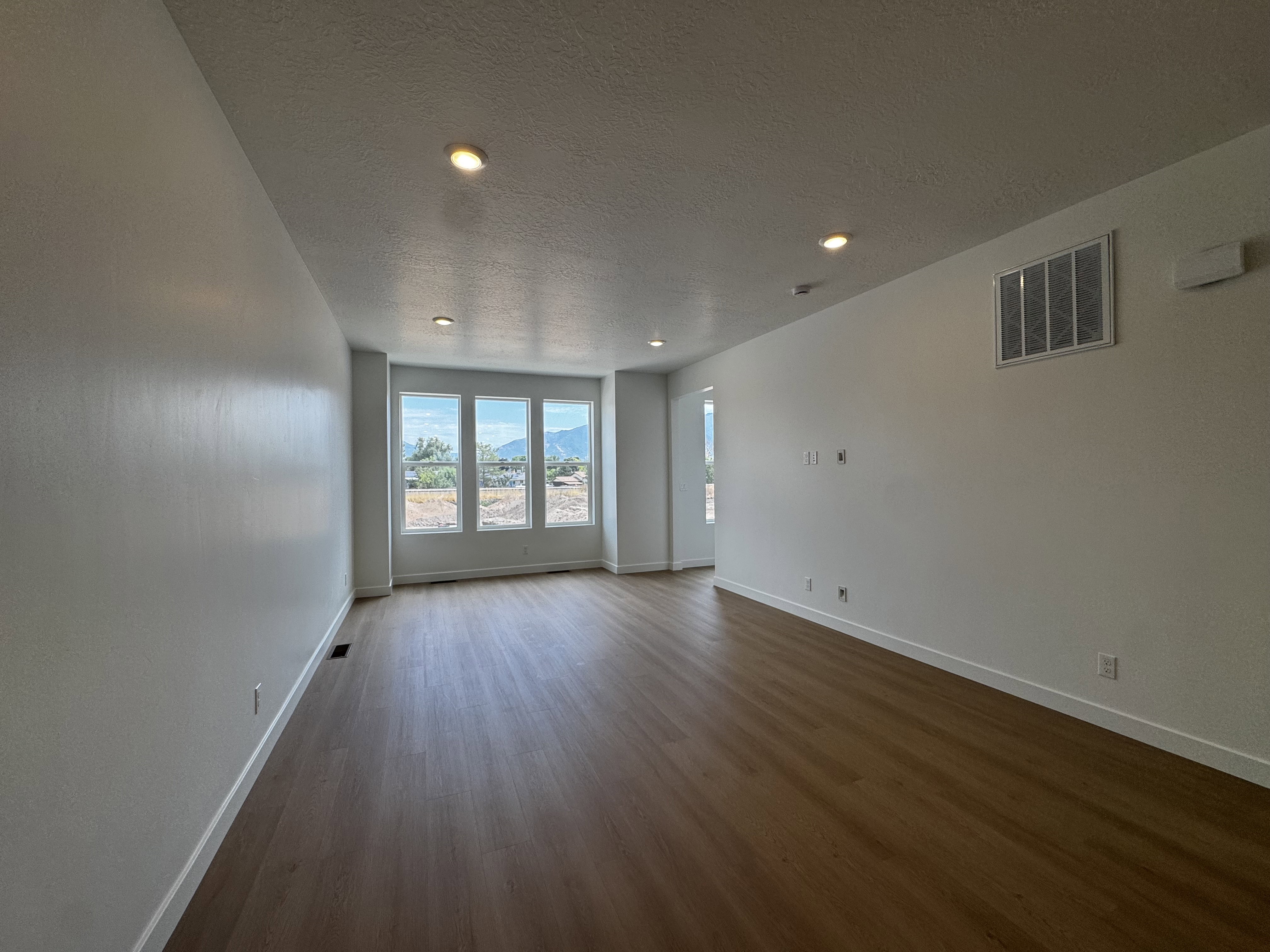 Bright interior space featuring wood-finish flooring, recessed ceiling lighting, and multiple windows