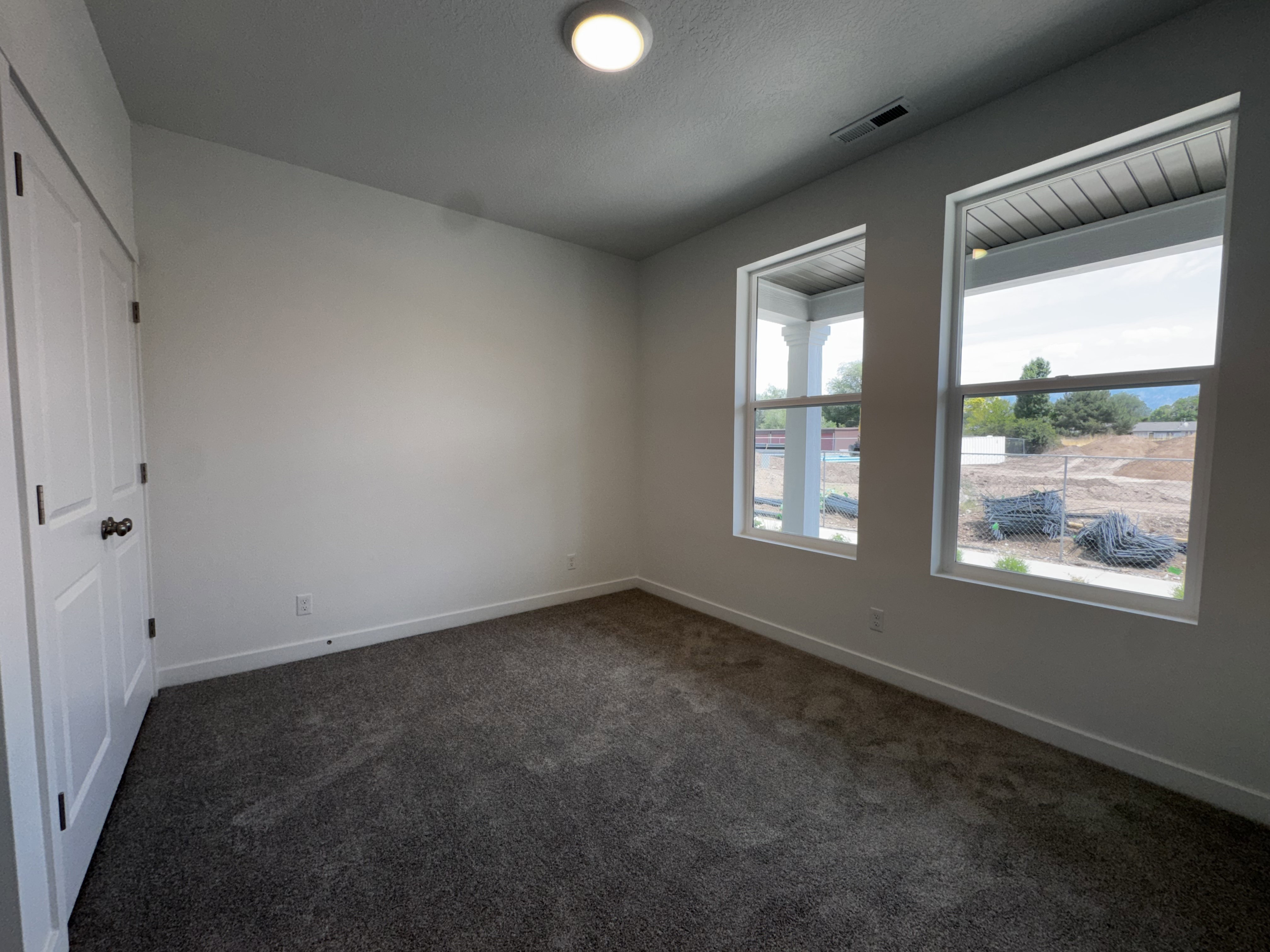 Interior room featuring light gray walls and dark gray textured carpeting