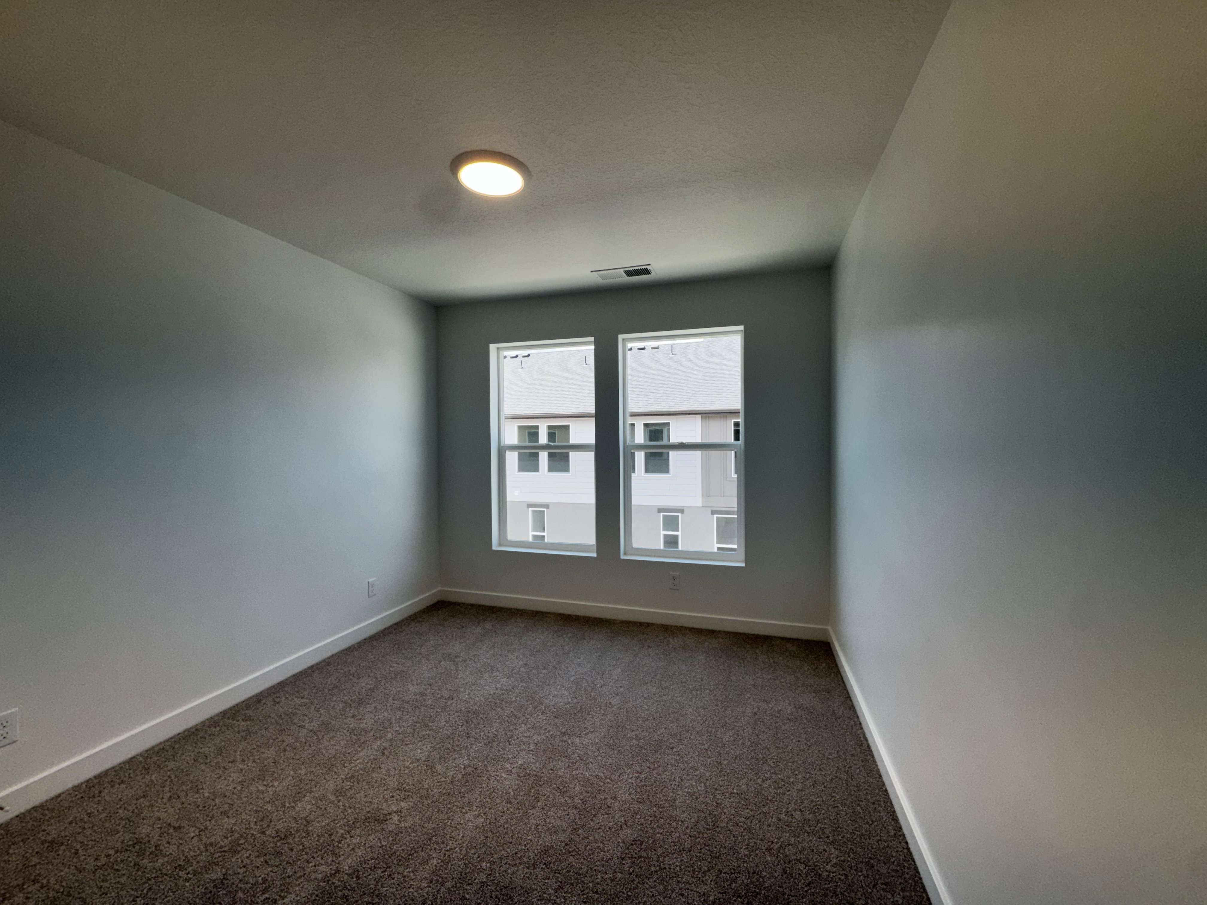Bright room featuring dual windows, recessed ceiling lighting, neutral-toned walls, and plush carpet flooring