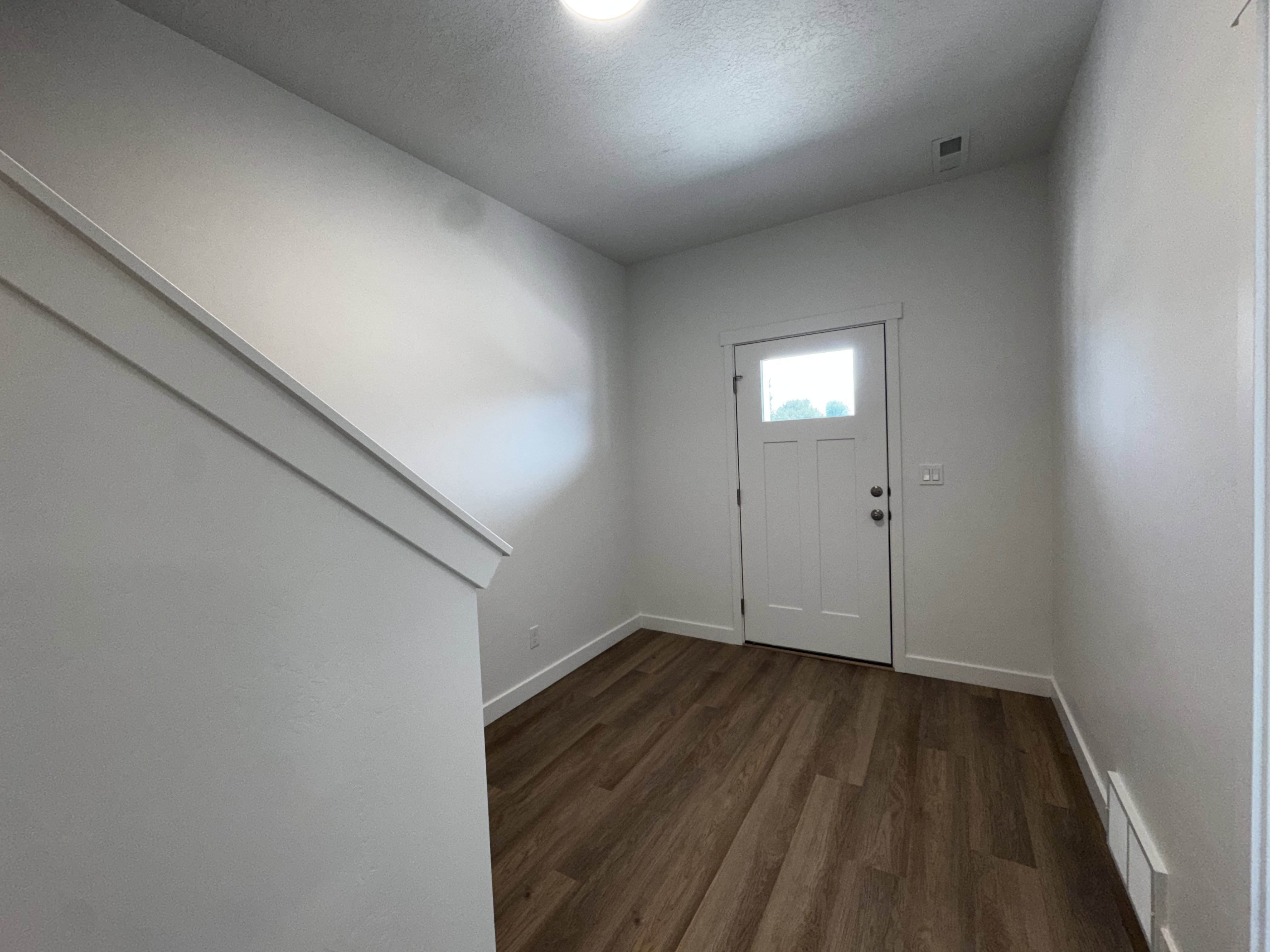 Entryway featuring wood-finish flooring, a white paneled door with an upper glass pane, and white baseboards