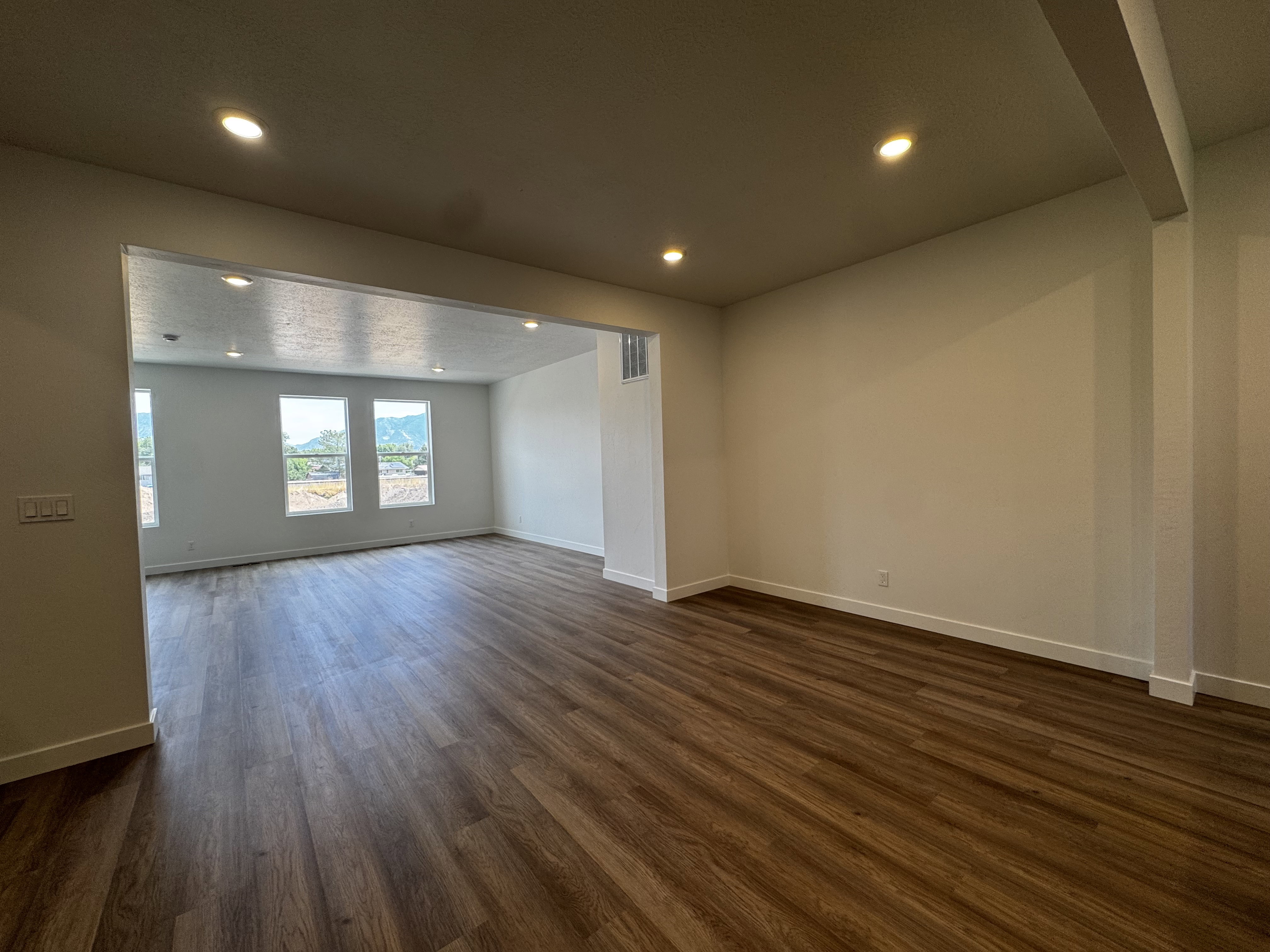 Open concept living area featuring wood-finish flooring, recessed lighting, and white baseboards