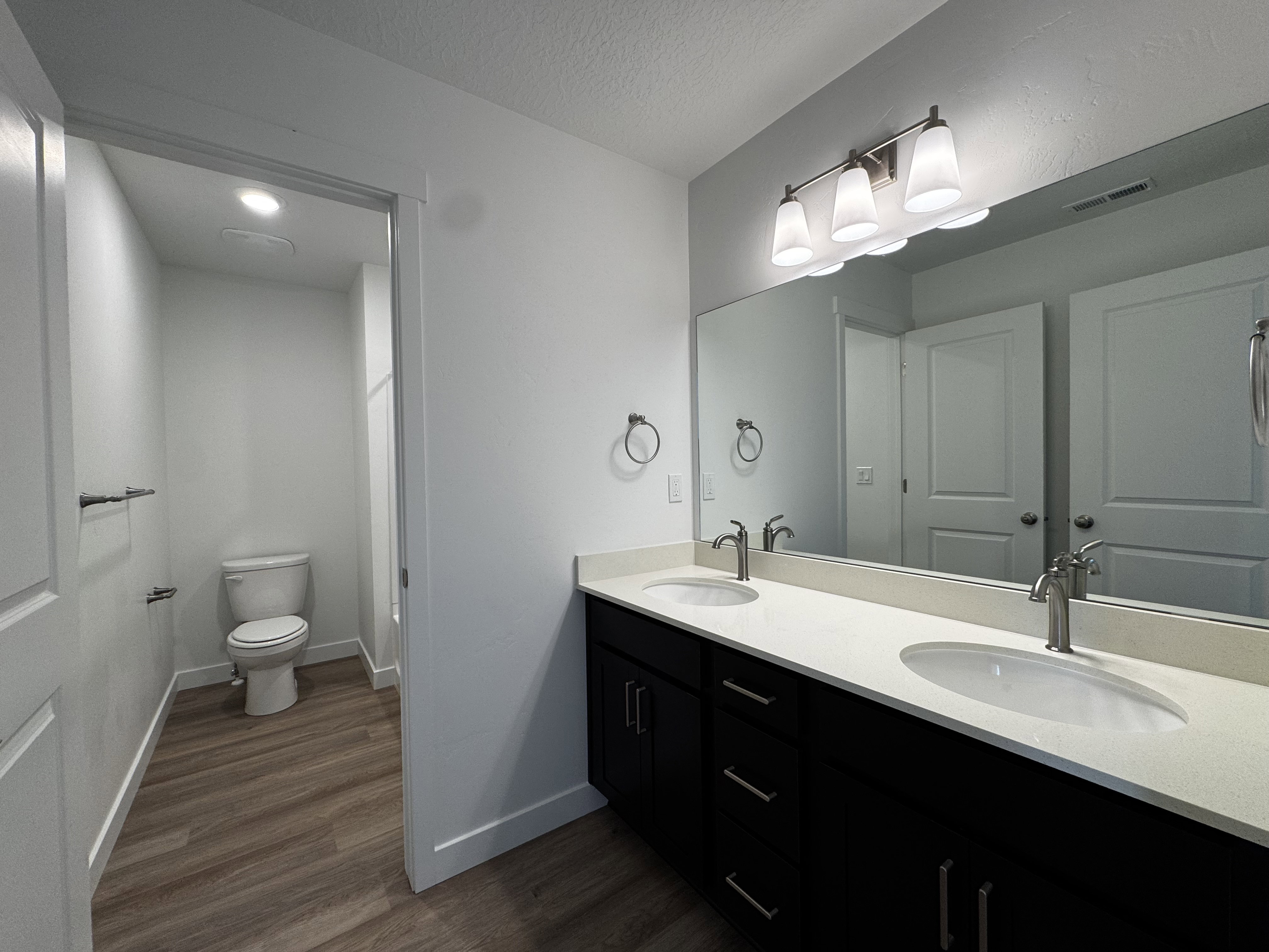 Bathroom featuring a dual vanity with dark cabinetry, integrated sinks, and light-toned countertops