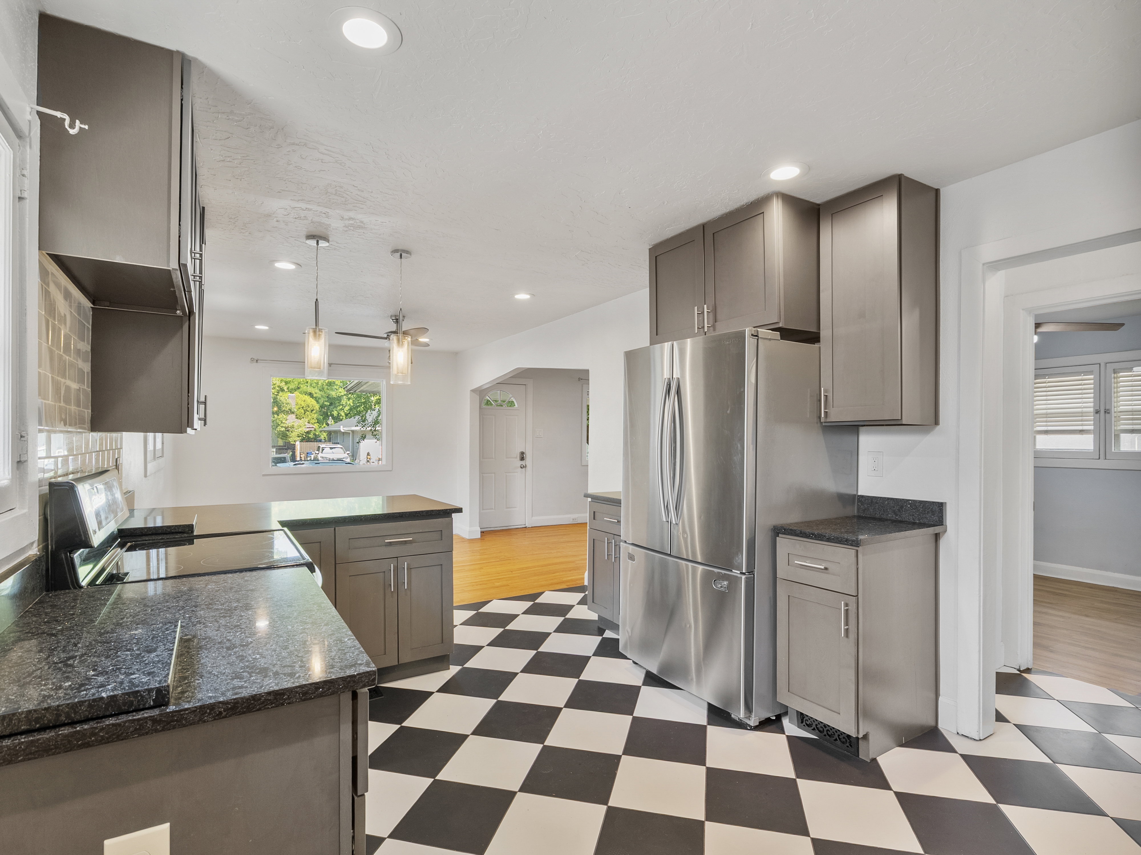 Kitchen featuring checkerboard flooring, stainless steel appliances, dark stone countertops, gray cabinetry, and recessed lighting