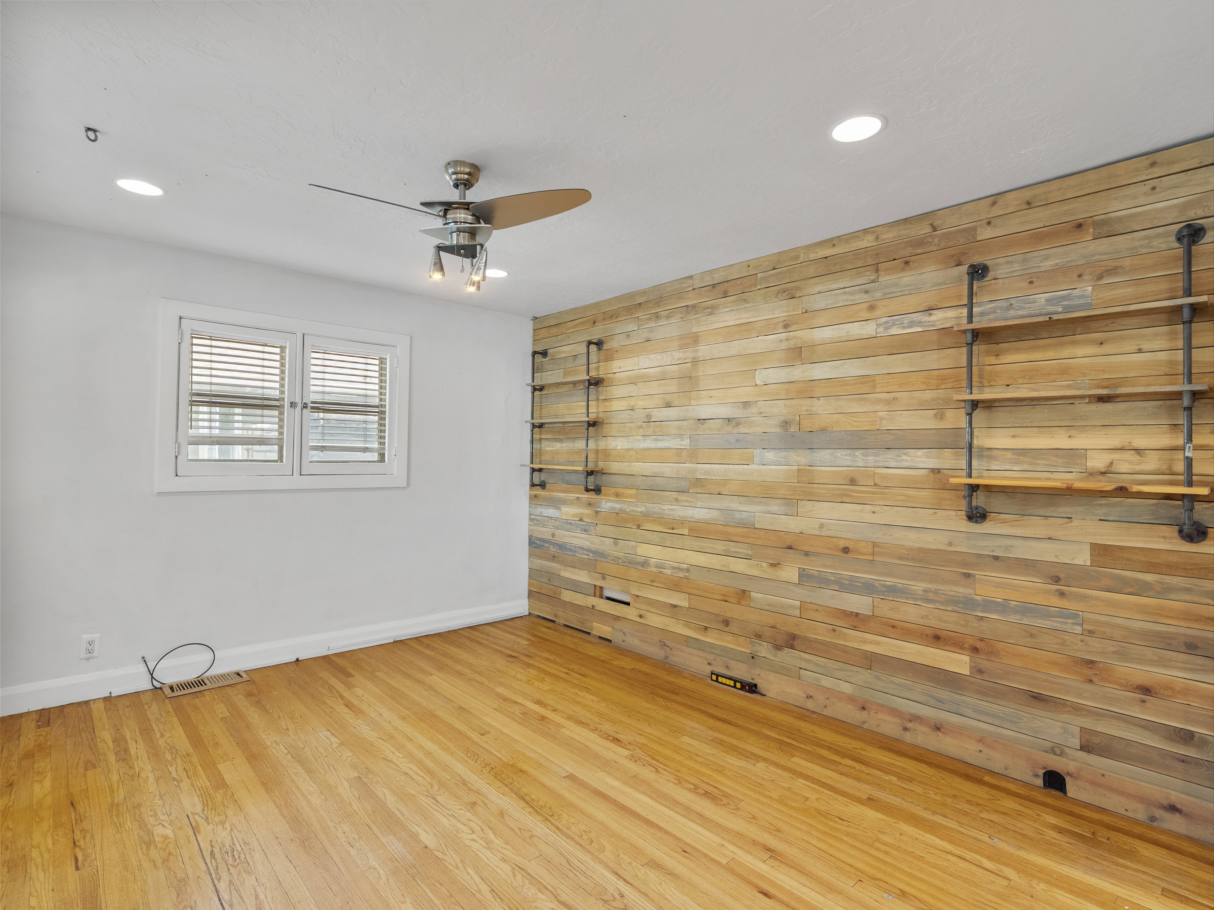 Accent wall featuring horizontal wood planks, wood-finish flooring, a ceiling fan with integrated lighting, recessed lighting, and a window with blinds