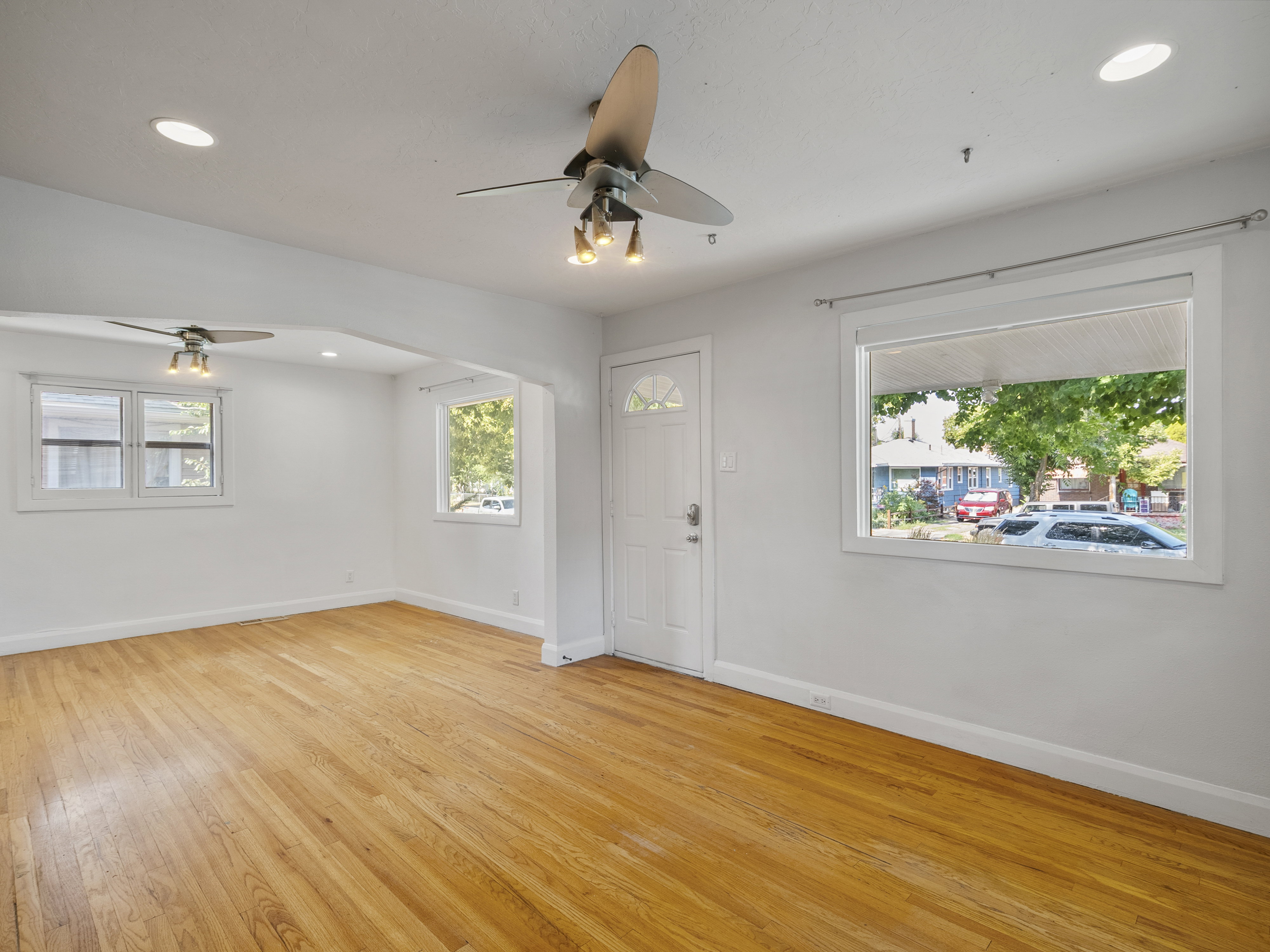 Spacious room featuring wood-finish flooring, white walls, and multiple windows
