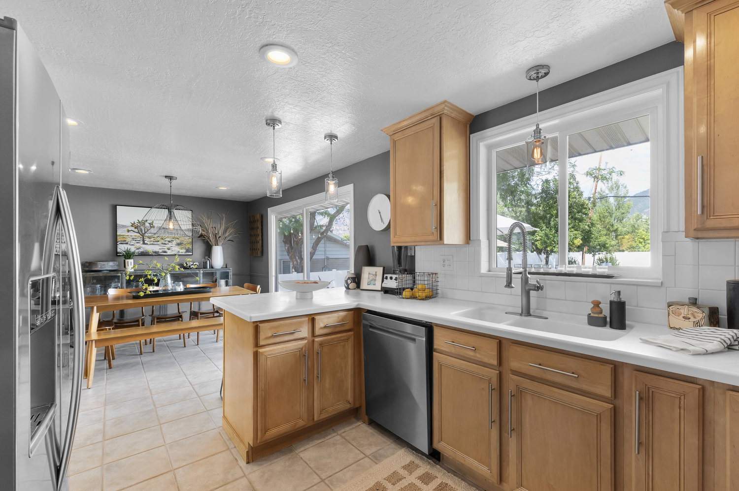 Kitchen featuring wood cabinetry, white countertops, tile flooring, a white subway tile backsplash, and a window with a mountain backdrop
