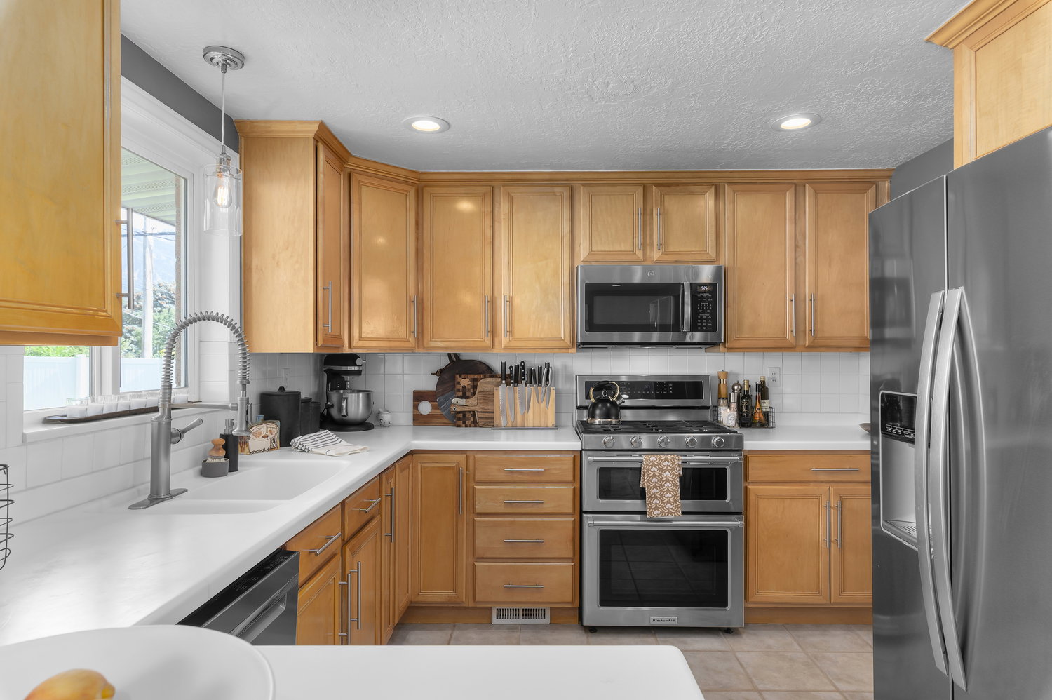 Kitchen featuring wood cabinetry, white countertops, stainless steel appliances, white subway tile backsplash, and recessed lighting