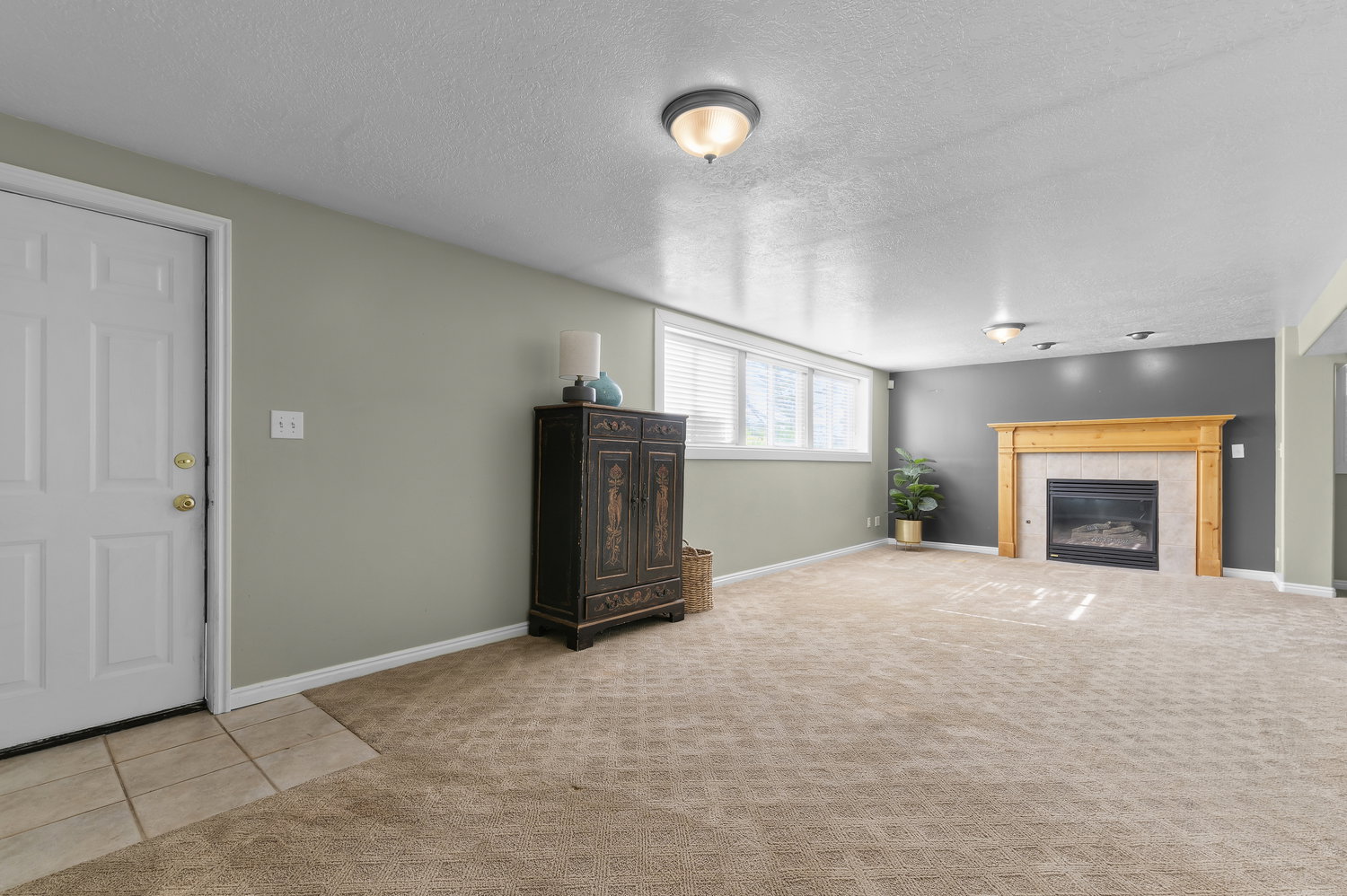 Carpeted living space featuring a fireplace with a light wood mantel and tile surround