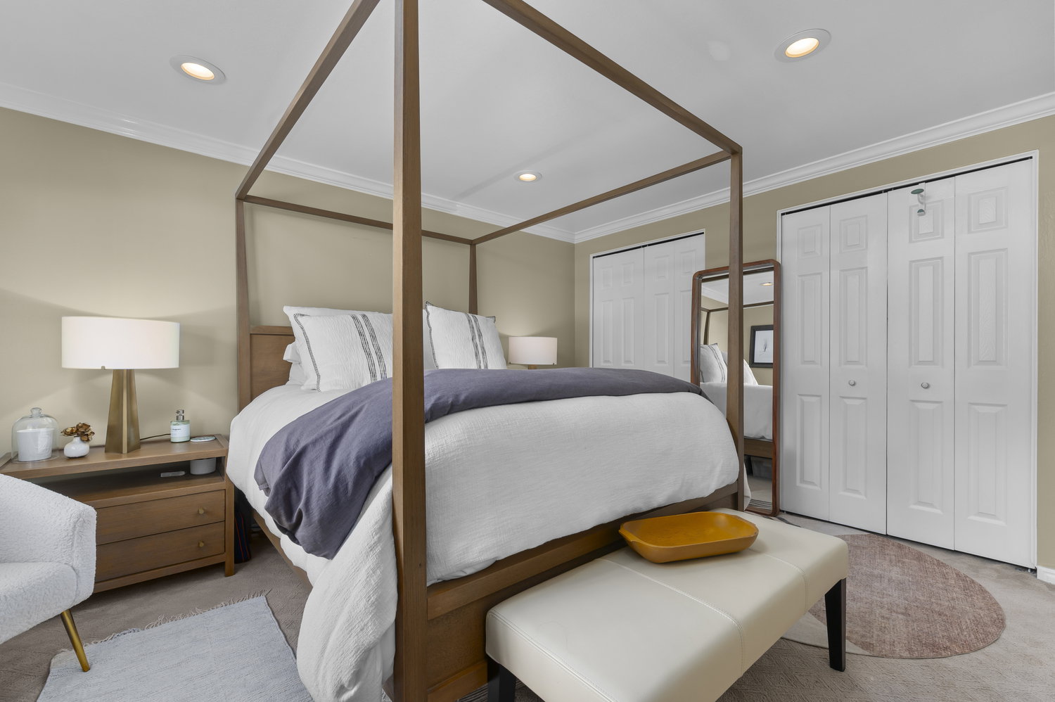 Recessed lighting illuminates this room featuring extensive crown molding, neutral wall tones, and two sets of bi-fold closet doors