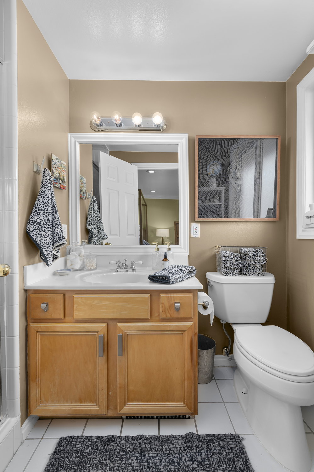 Bathroom vanity featuring a white countertop with an integrated sink, polished chrome faucet, and a large framed mirror with overhead lighting