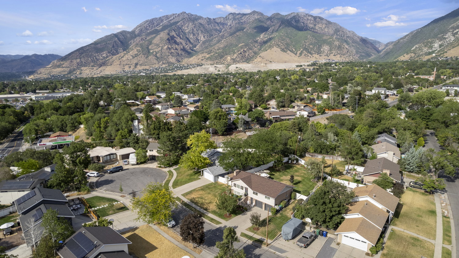 Residential properties interspersed with mature trees and landscaping, set against a prominent mountain range