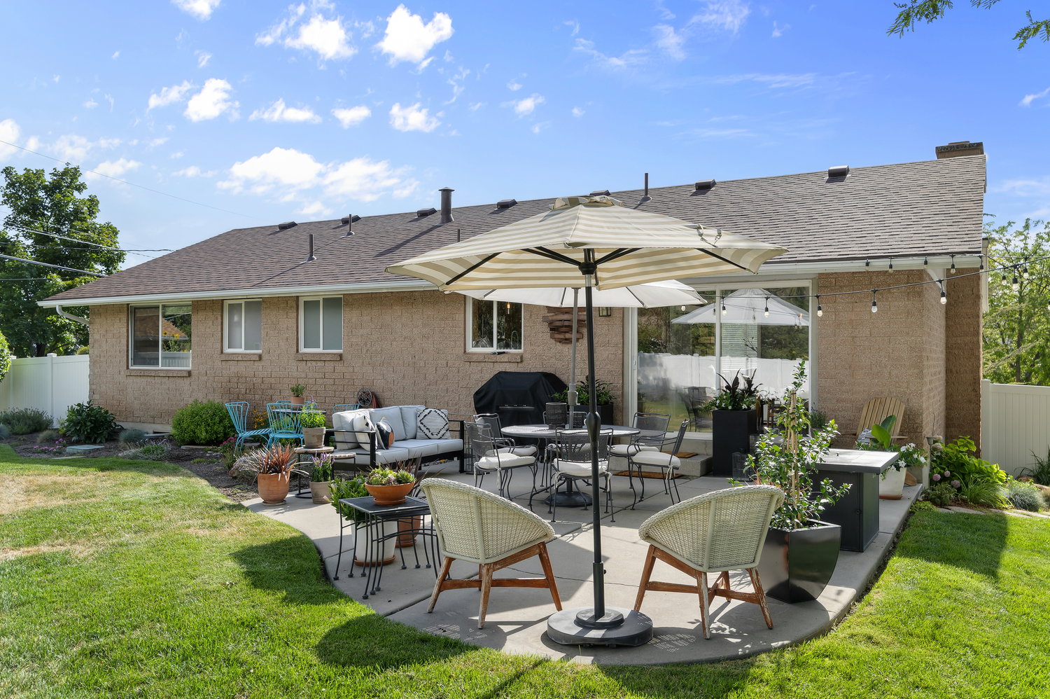 Expansive backyard featuring a curved concrete patio, manicured lawn, and mature perimeter landscaping