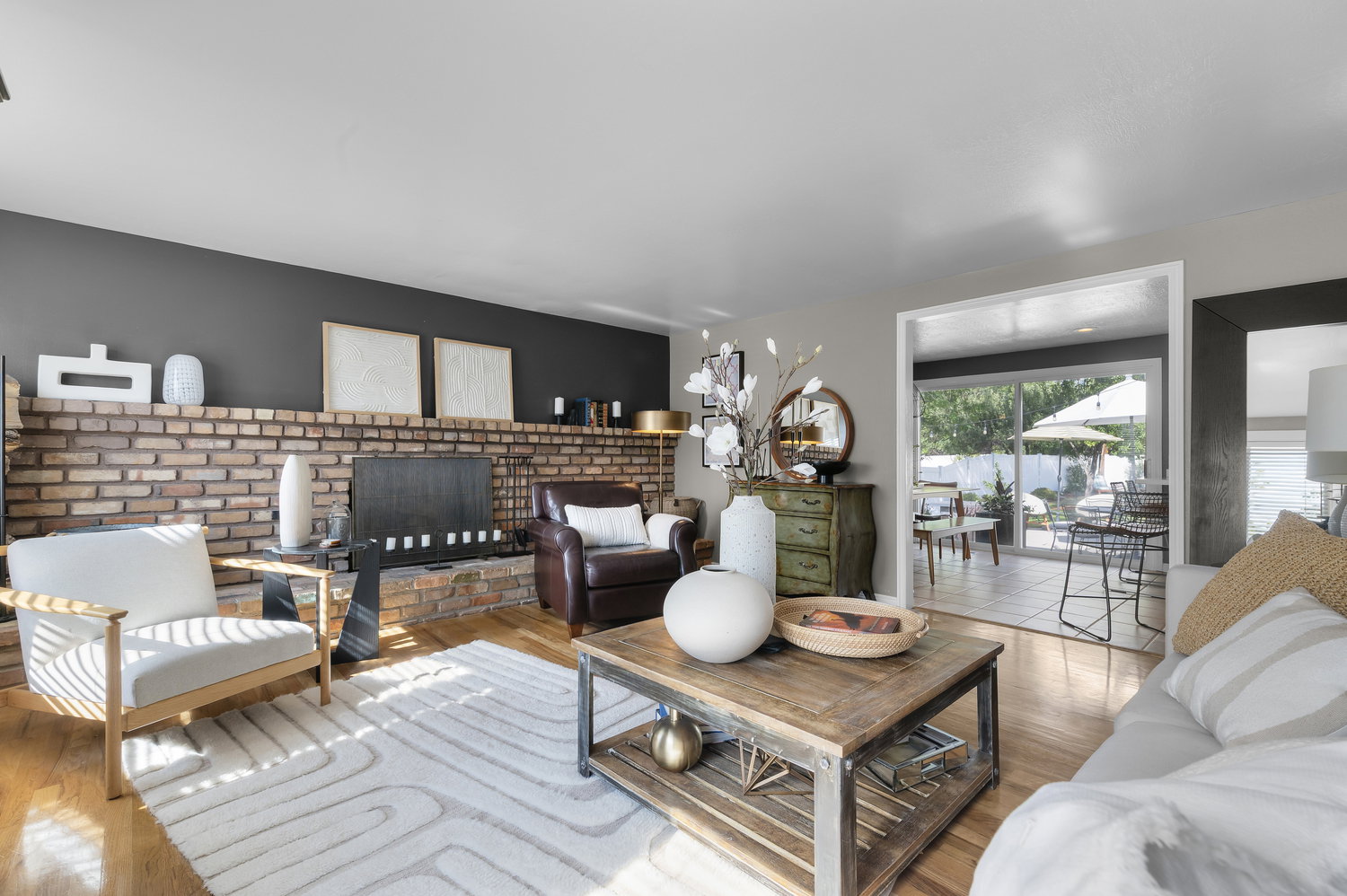 Living room featuring a brick fireplace with a raised hearth, wood-finish flooring, and a wide entryway to an outdoor patio with sliding glass doors