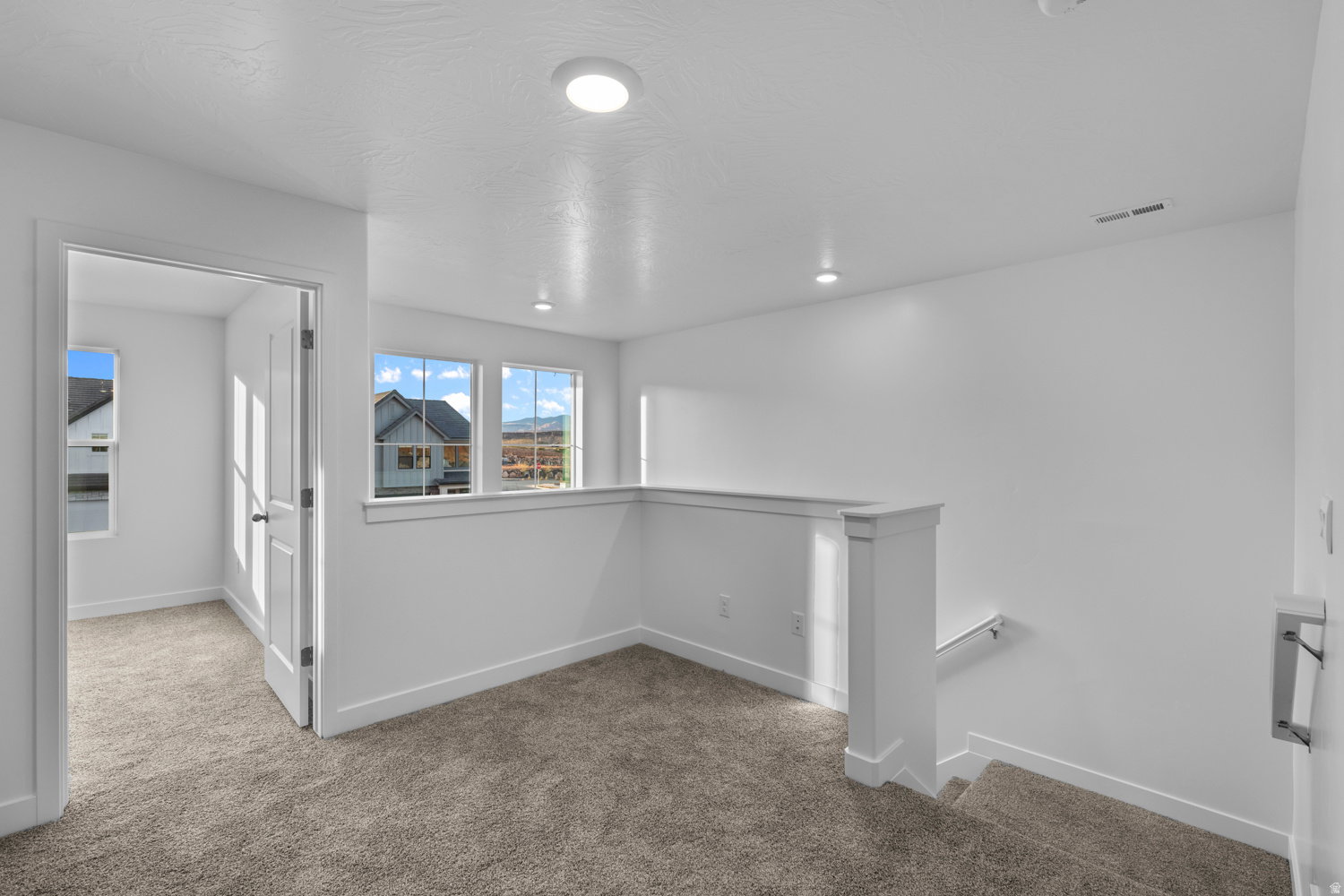 Upper-level landing featuring neutral carpet, white walls, and recessed lighting
