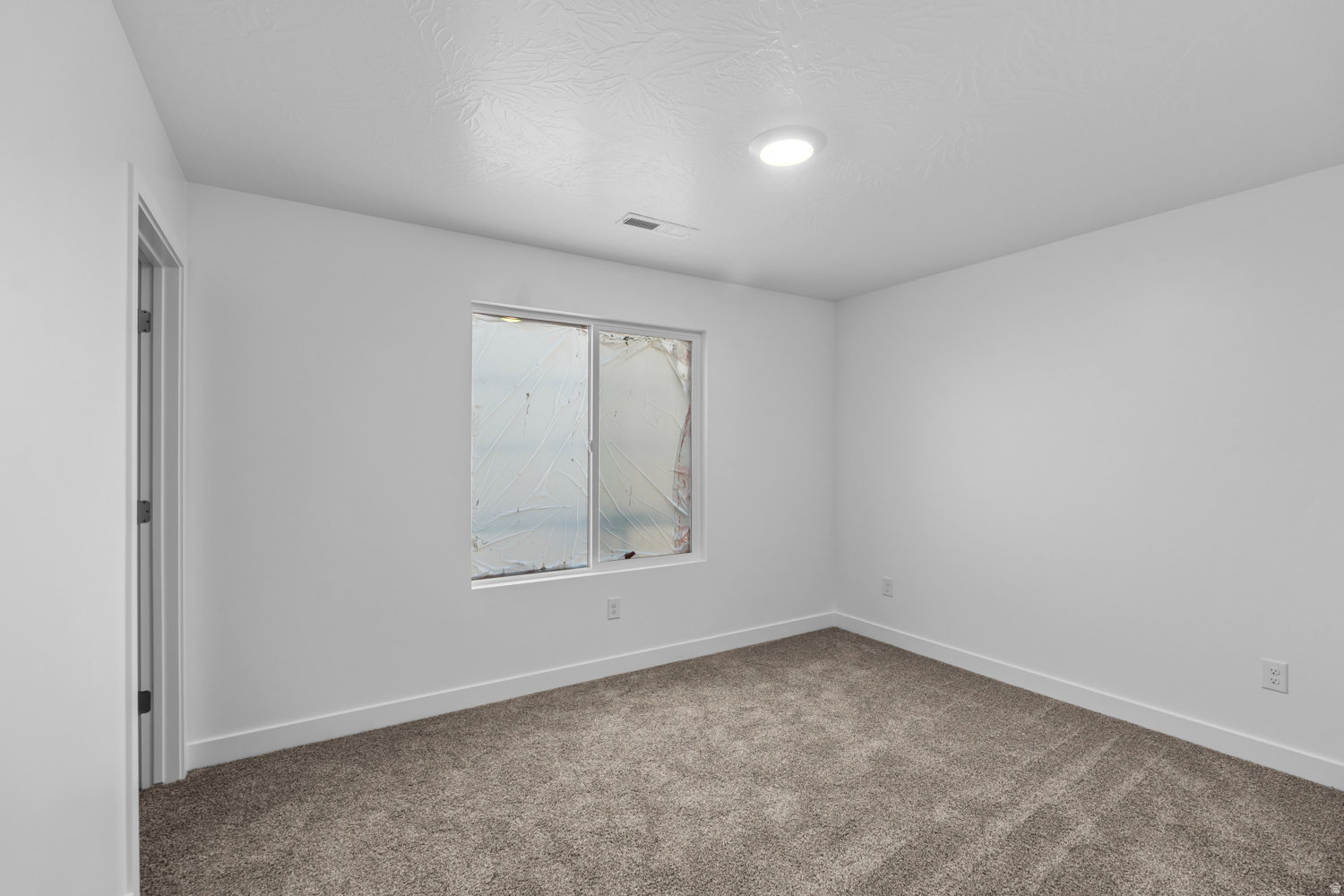Neutral interior featuring a recessed ceiling light, a window, and wall-to-wall carpeting