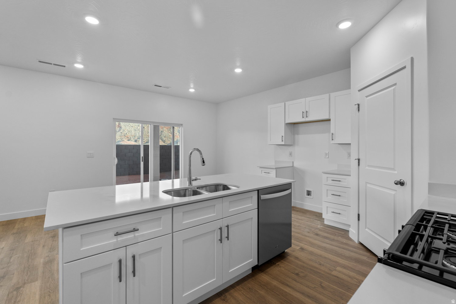 Modern kitchen island featuring a dual basin sink with gooseneck faucet, integrated dishwasher, and white shaker-style cabinetry